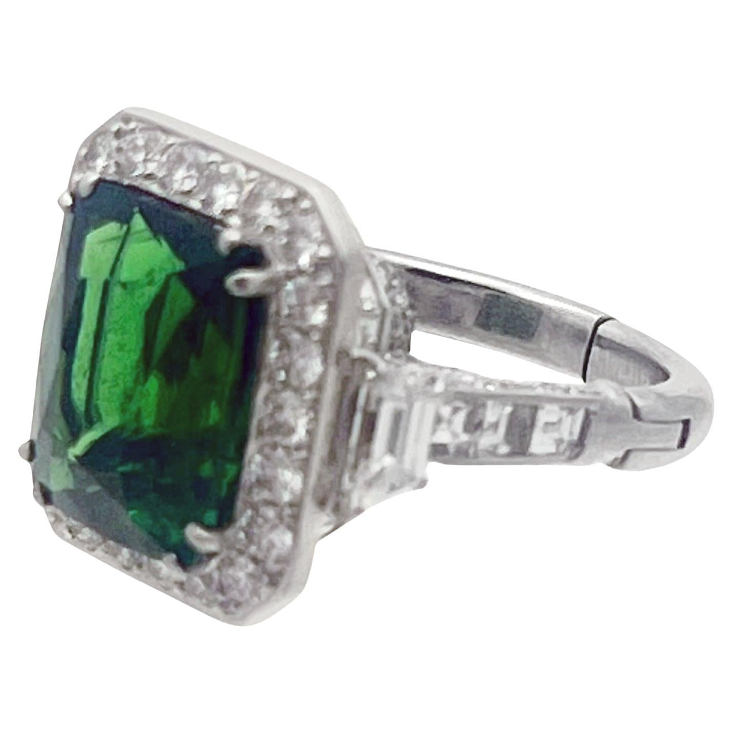 Vibrant green 10.29 carat tsavorite garnet set in a handmade platinum and diamond mounting by Robert Procop. Tsavorite garnet surrounded by twenty-two round brilliant-cut diamonds in a halo design. Two trapezoid-shaped diamonds accent the top sides,
