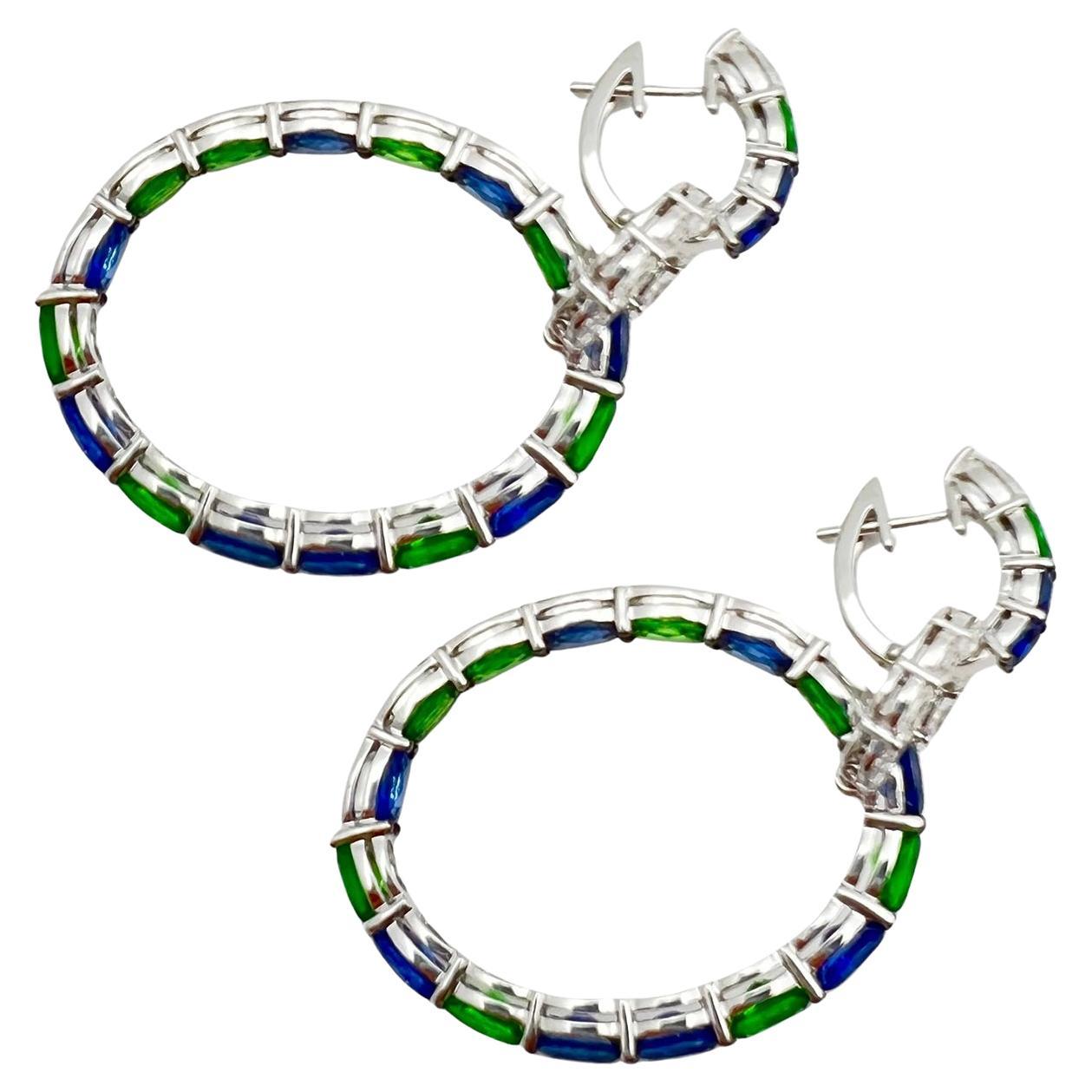 Part of Robert Procop's iconic American Glamour Collection, these triple hoop earrings showcase vibrant green tsavorite garnets, blue sapphires, and colorless diamonds in polished 18k white gold.  Eighteen oval faceted tsavorite garnets weighing