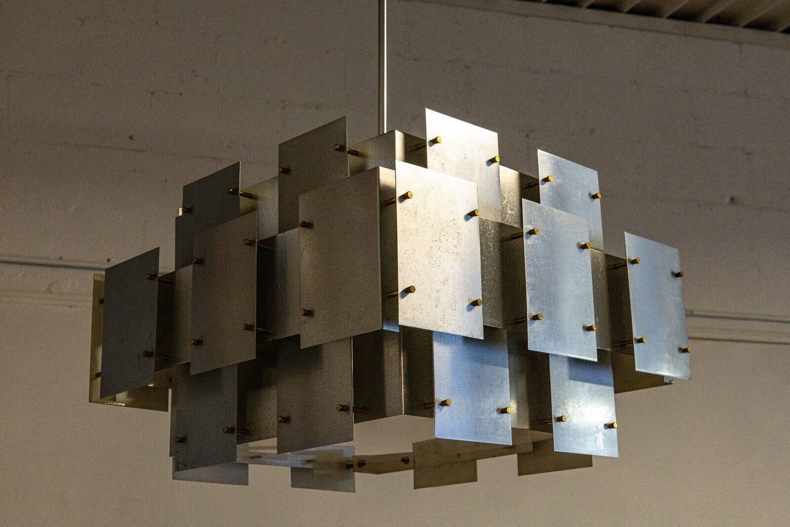 A Robert Sonneman cityscape brutalist brushed steel chandelier. This stunning chandelier is a great showcase of brutalist design in a lighting fixture. This piece is quite large and really demands a presance in a room. This chandelier features a