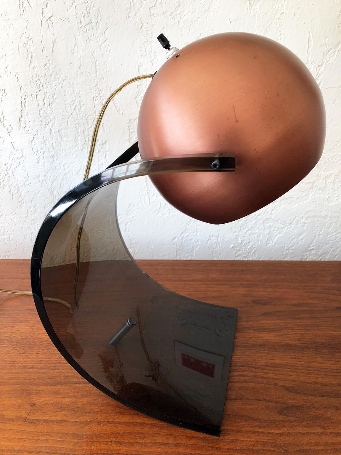 A wave of smoked Lucite rests on a single bronze leg and crests in a copper orb in this grand Mid-Century desk lamp by Robert Sonneman. A wonderful addition to a modern desk - at home or at the office.

Please Note: Pickup for this lamp is in