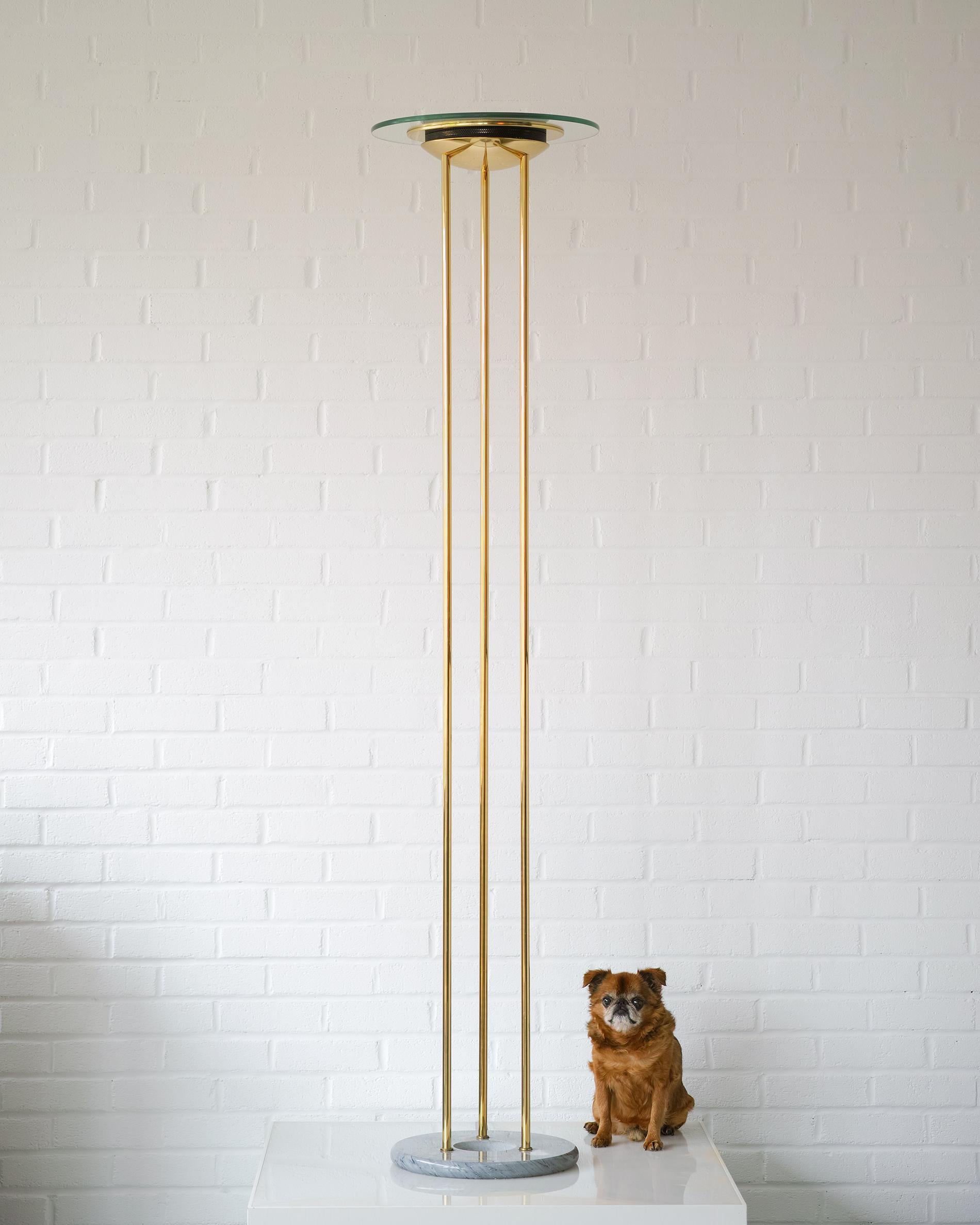 For your consideration is this circa 1992 post-modern torchiere floor lamp by Robert Sonneman for George Kovacs. It features a nicely weighted, solid gray marble donut base from which three polished brass plated tubes rise to support a brass plated