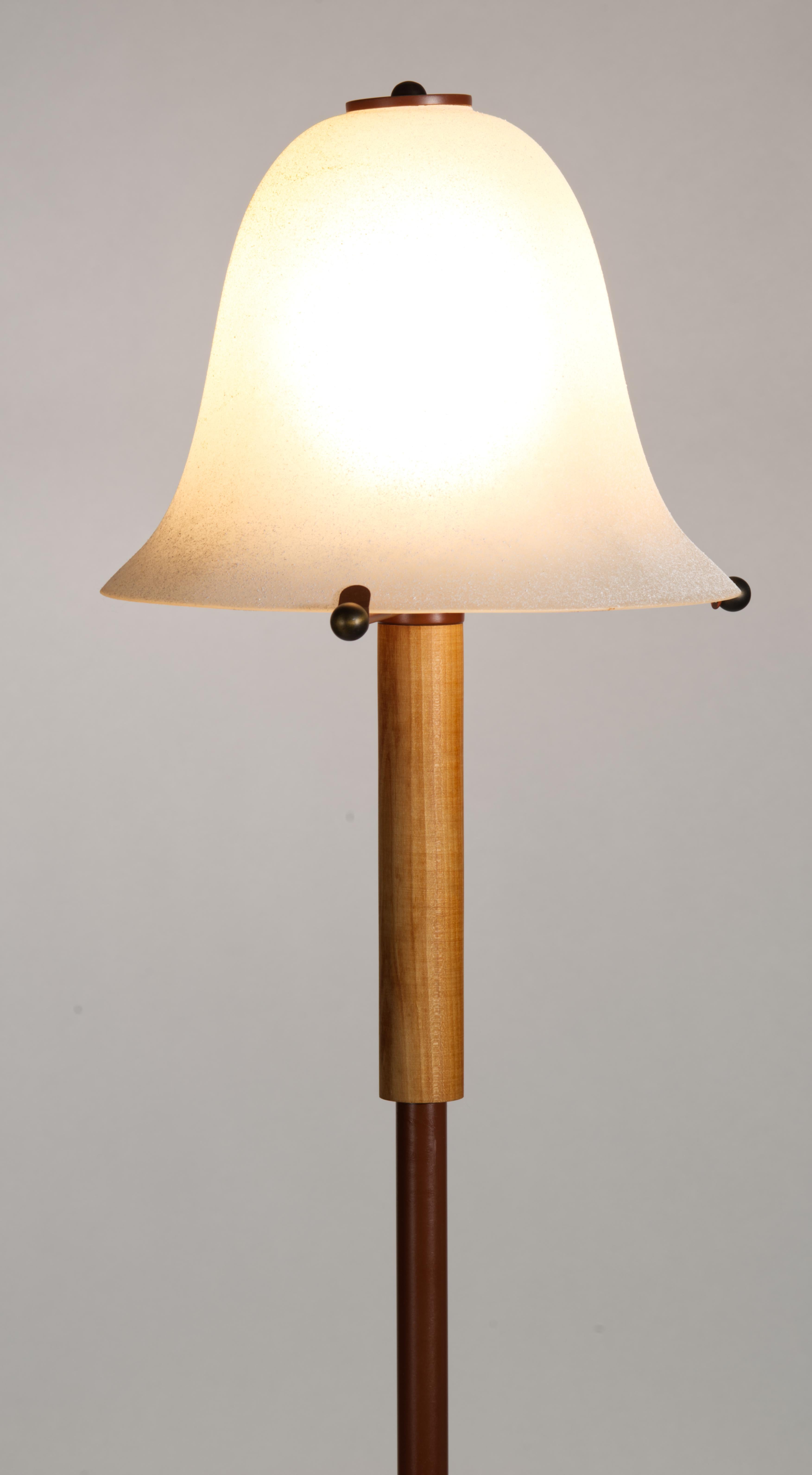  Vintage floor lamp or torchiere features a streamlined design with frosted, sandblasted opaque glass shade on enameled metal base with solid wood accent. The color palette of the mocha brown enamel and natural fruitwood tones harmonize with the