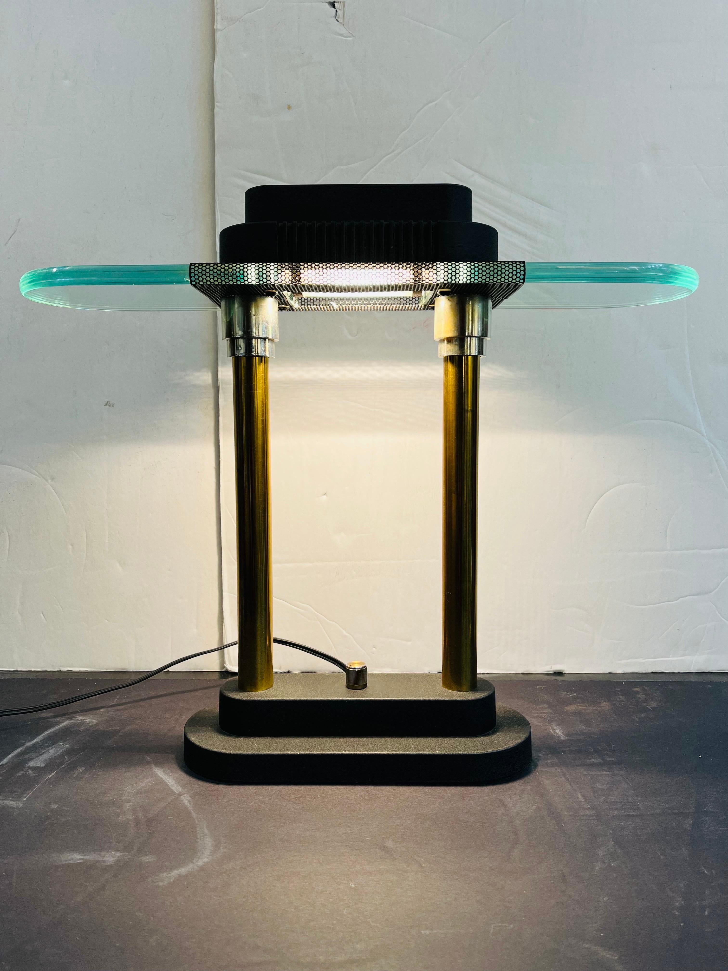 A vintage, post modern style bankers desk lamp by Robert Sonneman for Kovacs. This post Memphis era table lamp was inspired by Ettore Sottsass' design for his Pausania lamp. The Sonneman table lamp features a thick glass top, brass and chrome