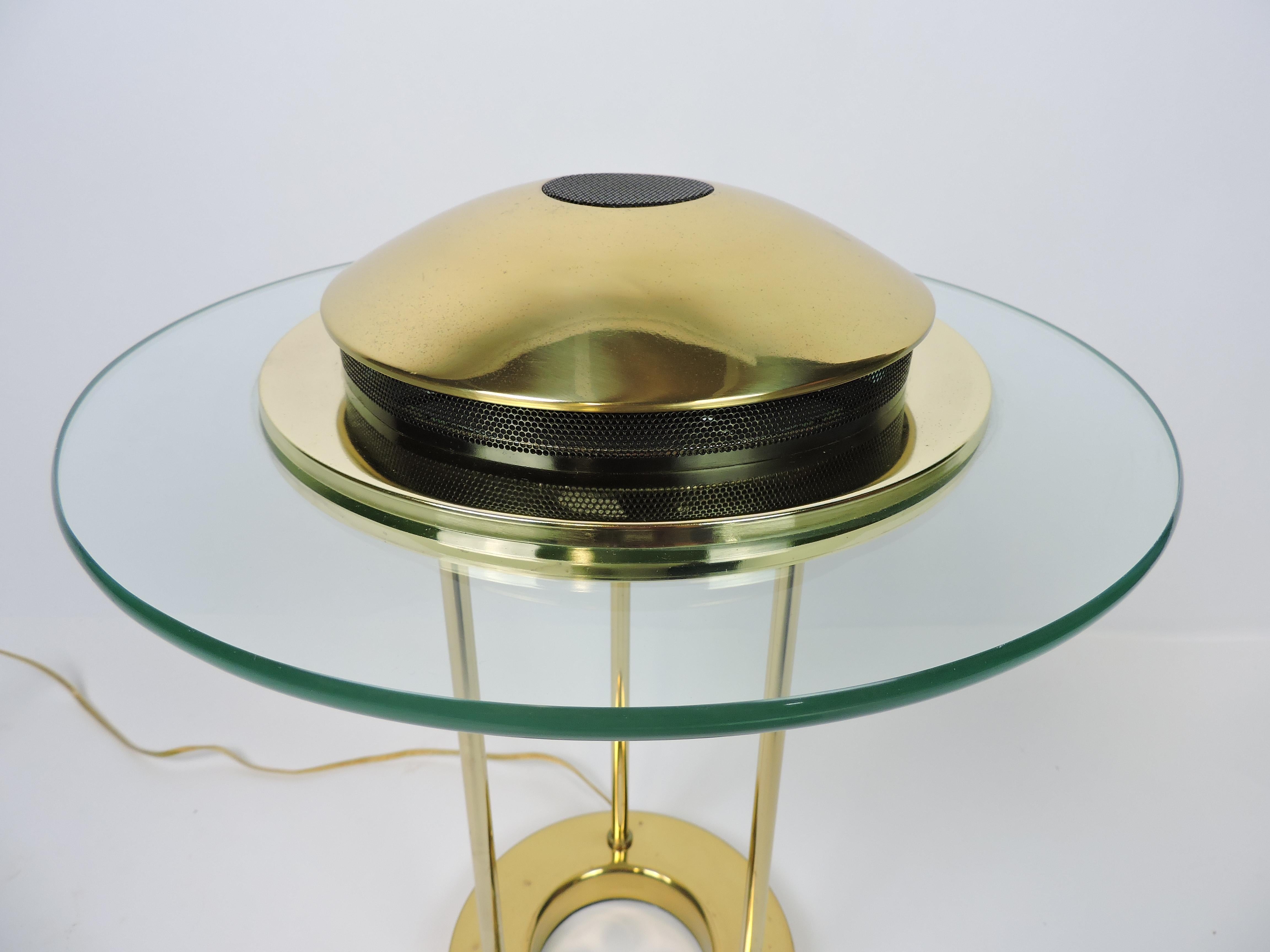 Very cool and iconic brass and glass Saturn desk lamp from the 1980s designed by Robert Sonneman for George Kovacs. This lamp has a round glass disc with a domed top that's supported by three columns on a circular base. It has an on/off dimmer