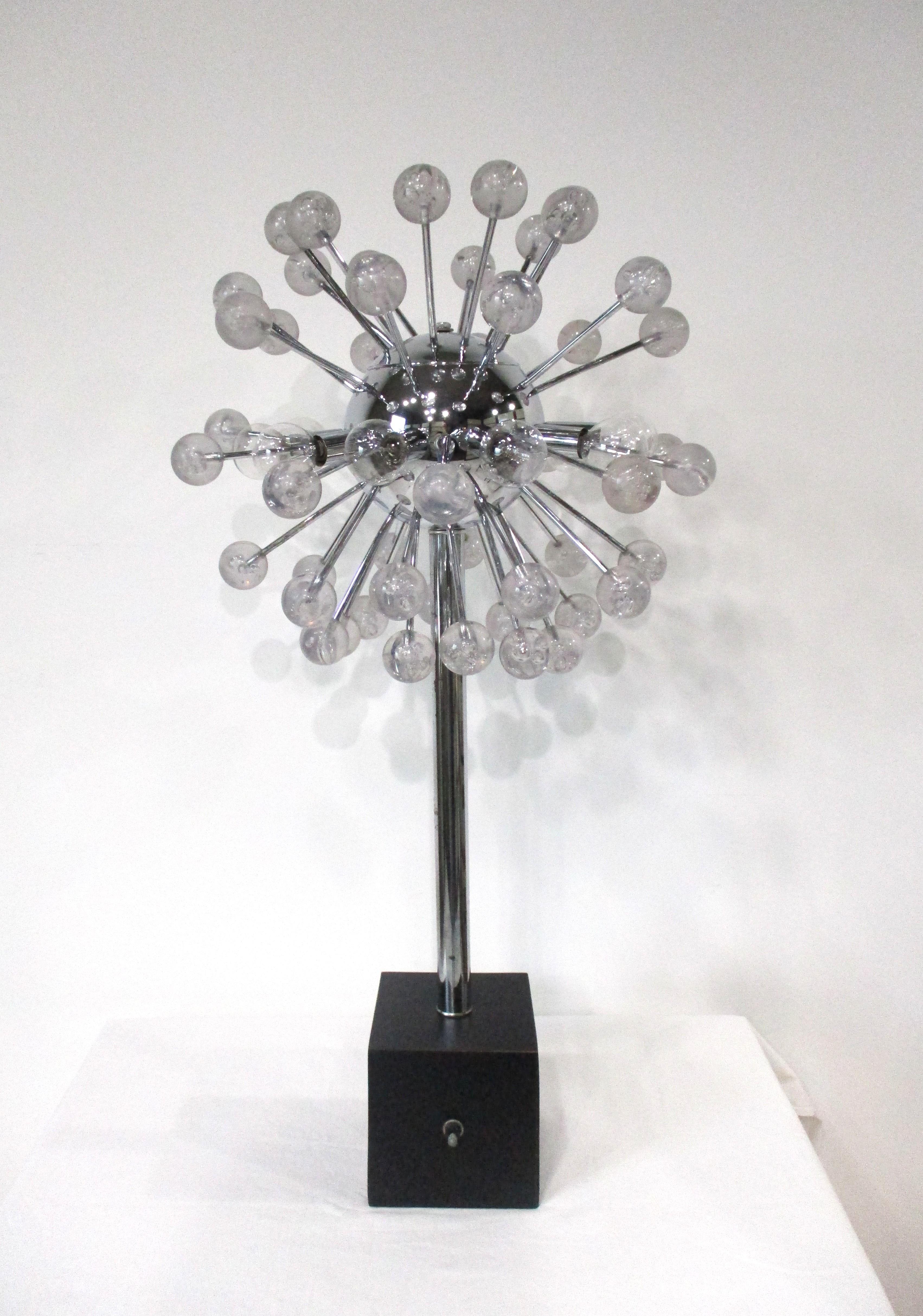 Una lámpara de sobremesa única de la Era Espacial con grandes bolas de Lucite a las que se han añadido burbujas en su interior, de modo que cuando se encienden resultan muy llamativas. Al tener una bola cromada con palos cromados que sujetan cada