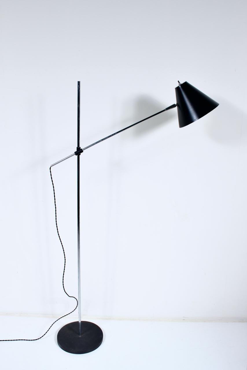 Moderne Robert Sonneman Style verstellbare Stehlampe zum Lesen. Ausgestattet mit einem verchromten Stahlrohrstiel, einem freitragenden Arm, einem schwarzen Drehknopf, einem verstellbaren, belüfteten, schwarz emaillierten Aluminium-Kippkonusschirm