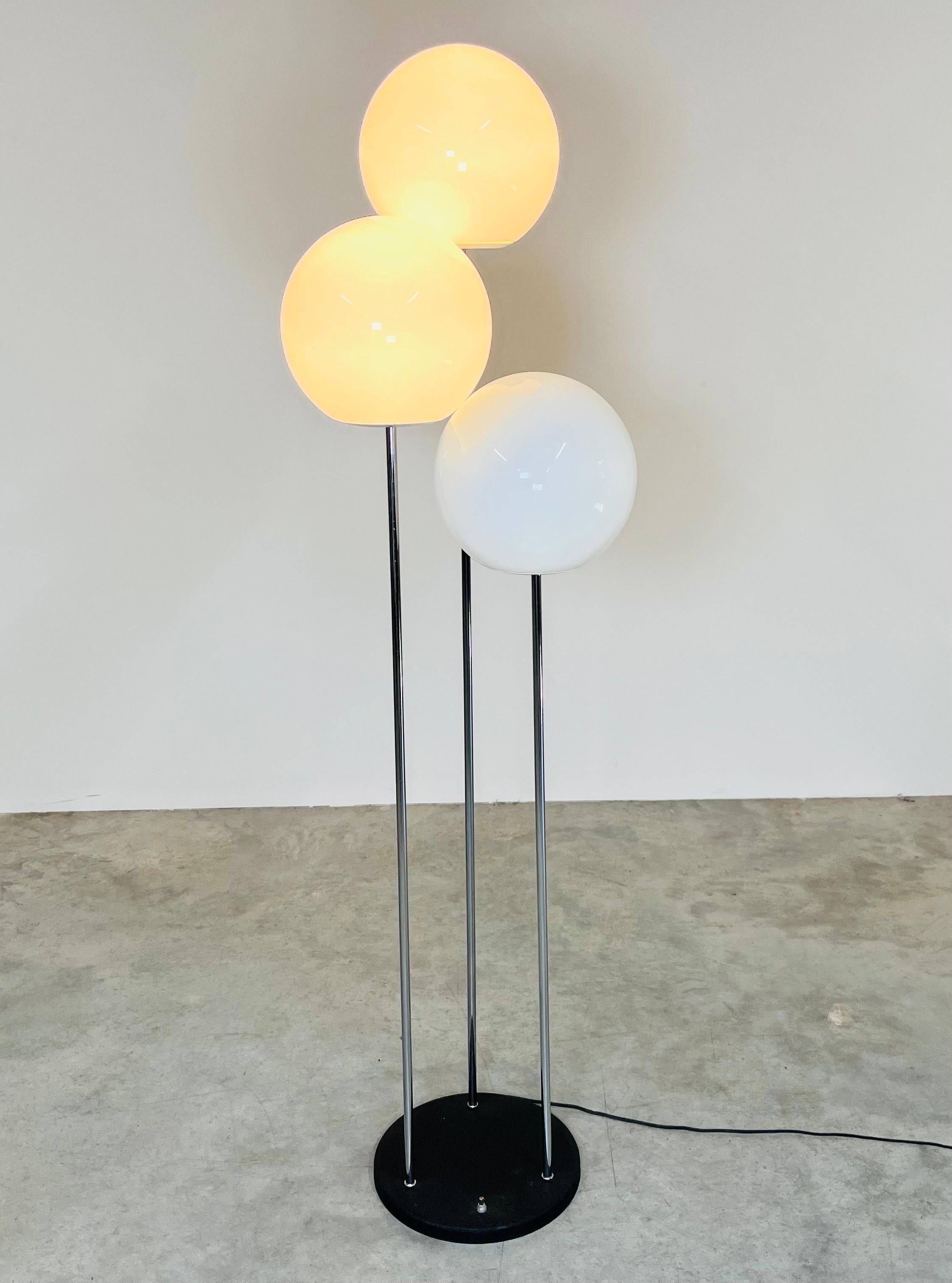 A beautiful triple stem “Lollipop” floor lamp designed by Robert Sonneman having chromed steep stems that lead to 3 independent milk glass globes all standing over a black textured steel base having a 3-way foot switch that triggers a single, double