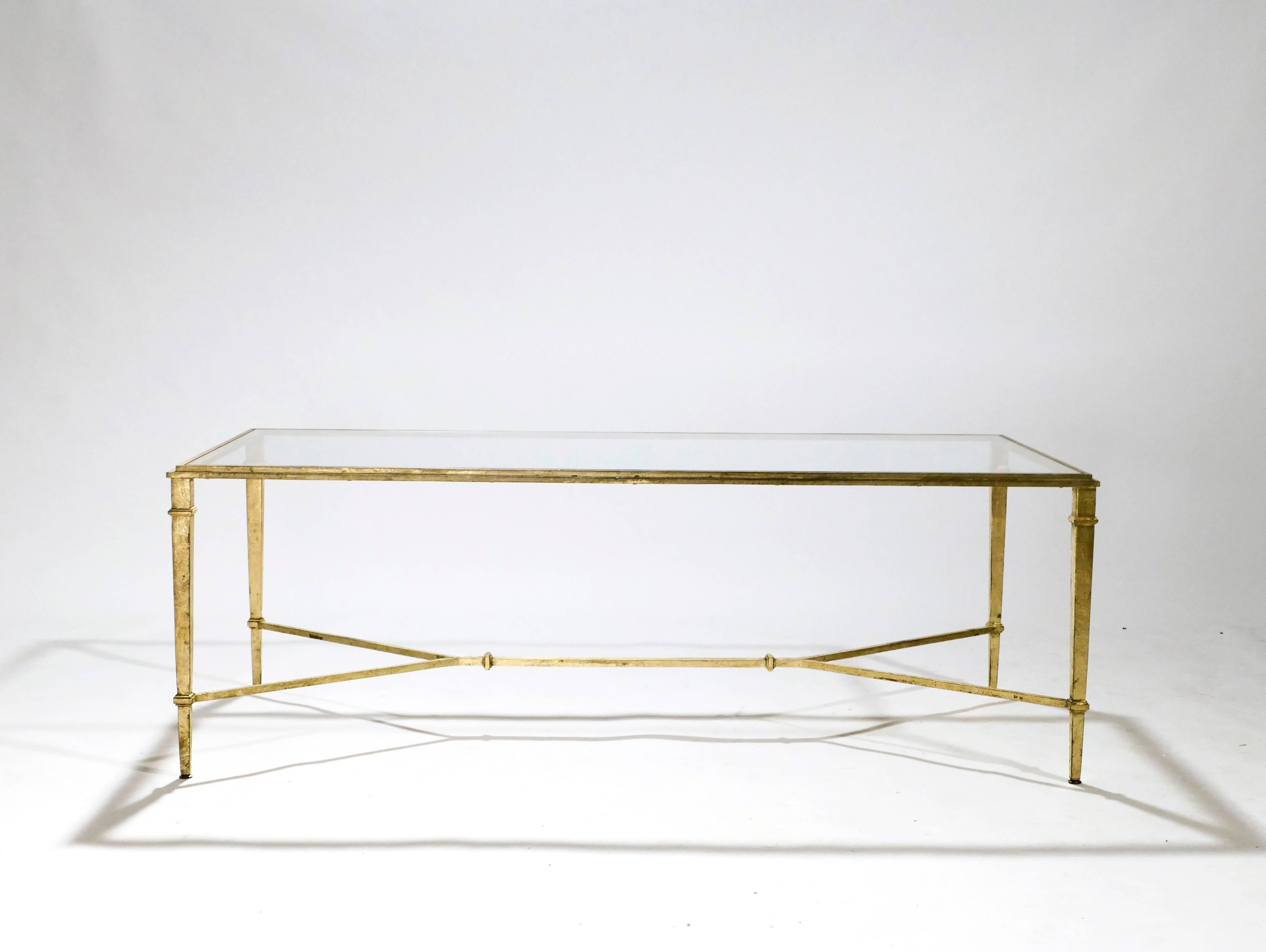 Grace your home with the true elegance of this coffee table signed and stamped by Robert Thibier. Glittering in an antiqued gold gilt finish, this iron craft coffee table adds a glam twist which makes a gracious compliment to both traditional and