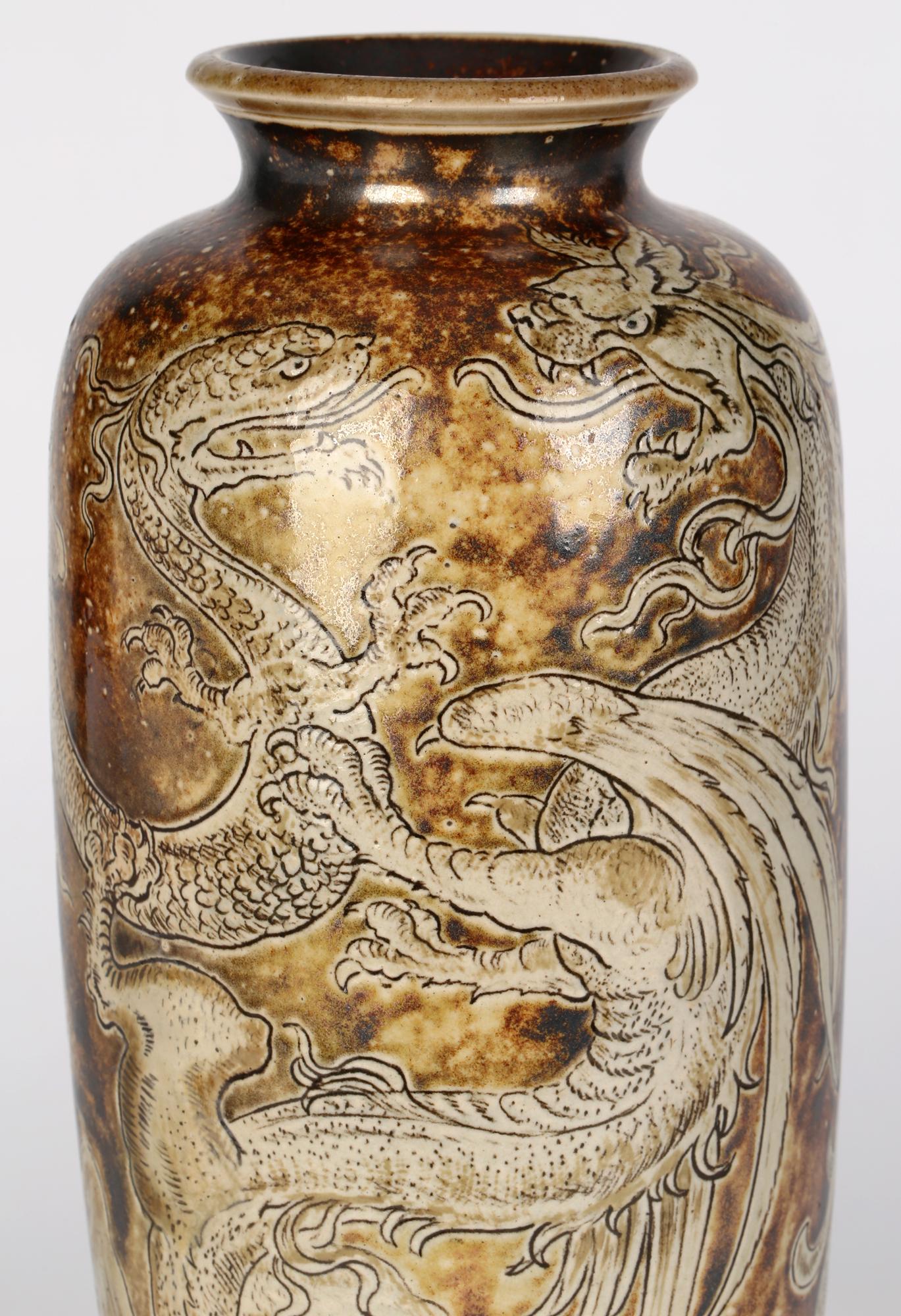 Un grand et impressionnant vase en grès décoré de dragons en duel, conçu par Robert Wallace Martin pour Martin Brothers et daté de 1896. Le grand vase à corps ovoïde repose sur un étroit pied de piédestal arrondi, avec des épaules étroites et un col