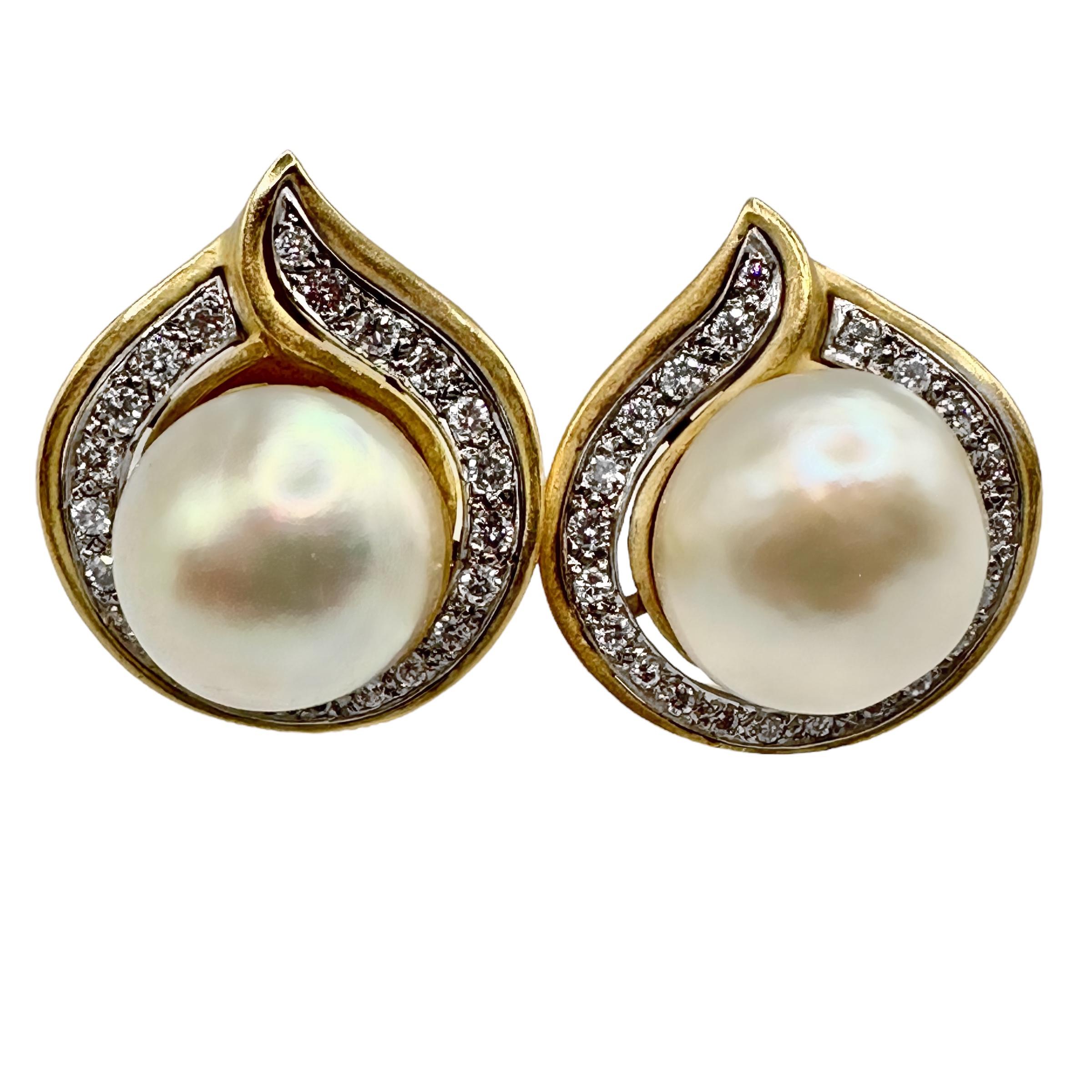 This very versatile pair of late-20th century 18K yellow gold designer fashion earrings is set with two 13.5mm semi-baroque South Sea pearls surrounded by a line of brilliant cut diamonds, set in white gold plates.  They can be worn alone or as tops