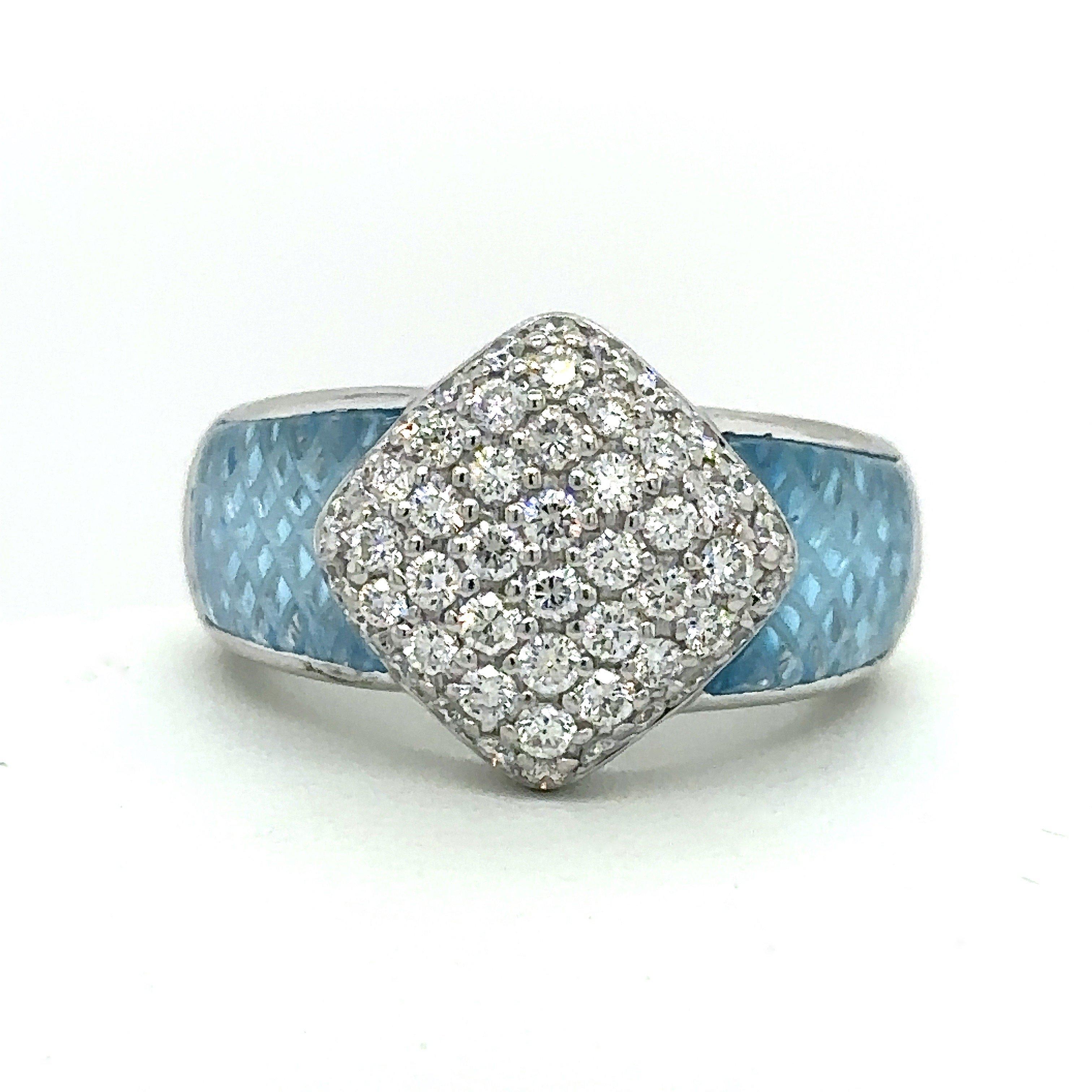 This 18KT white gold ring was designed by Robert Wander for WINC creations. It features approximately 1.25CT round diamond surrounded by blue topaz with a unique lattice carved design. The diamond front of the ring measures 14mm and the shank tapers