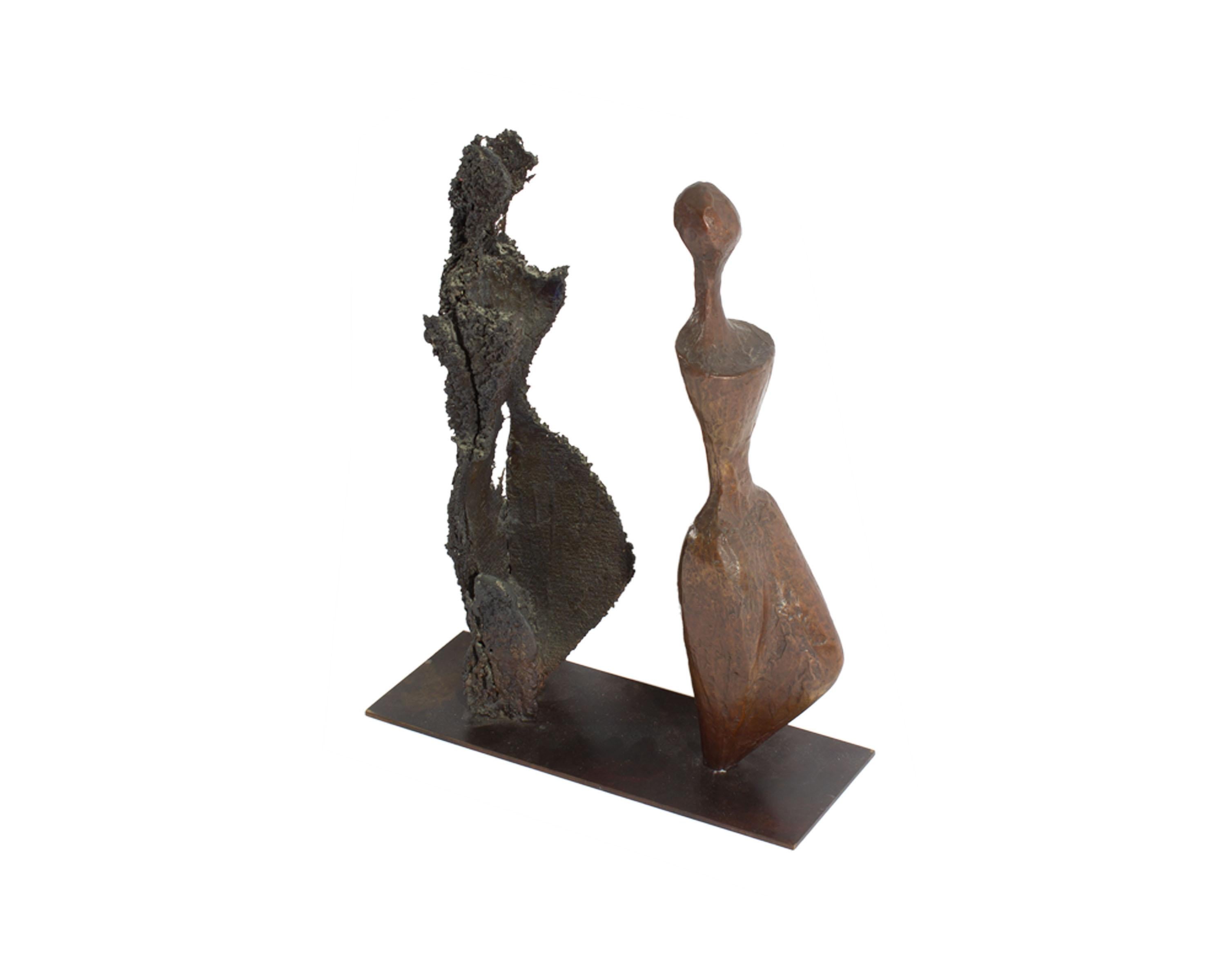A limited edition bronze sculpture titled ﻿Emerging ﻿by the American artist Robert X. Holmes (born 1927). A bronze figure stands in front of a darker figure positioned identically with the latter figure appearing to be the shadow of the leading