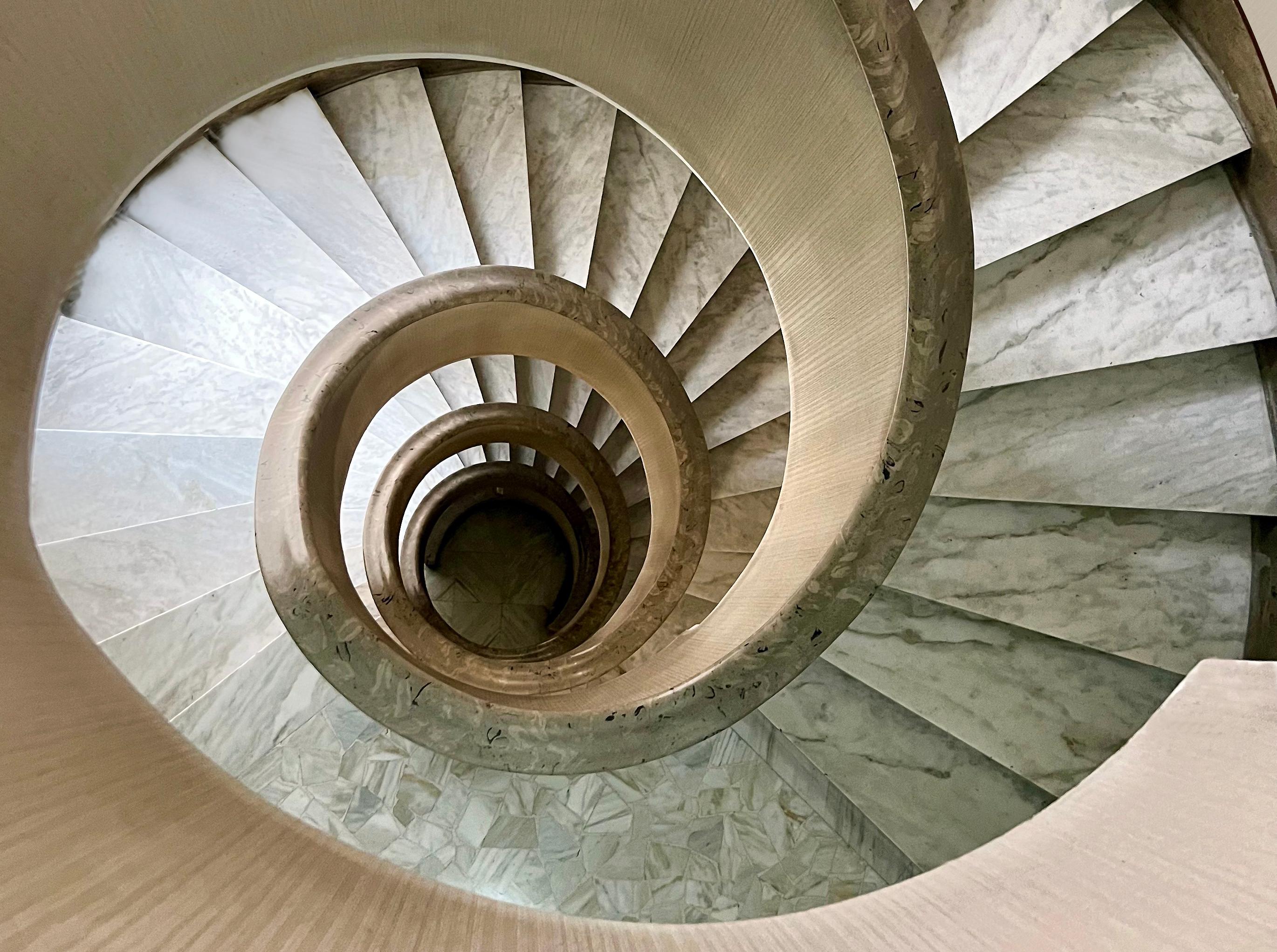 For a contemporary color photograph of a spiral staircase in Rome, Italy by Roberta Fineberg (RF), the artist captures a symmetrical cylindrical stairwell in the Eternal City. For the Cities series RF often travels to Europe, with Rome very much at