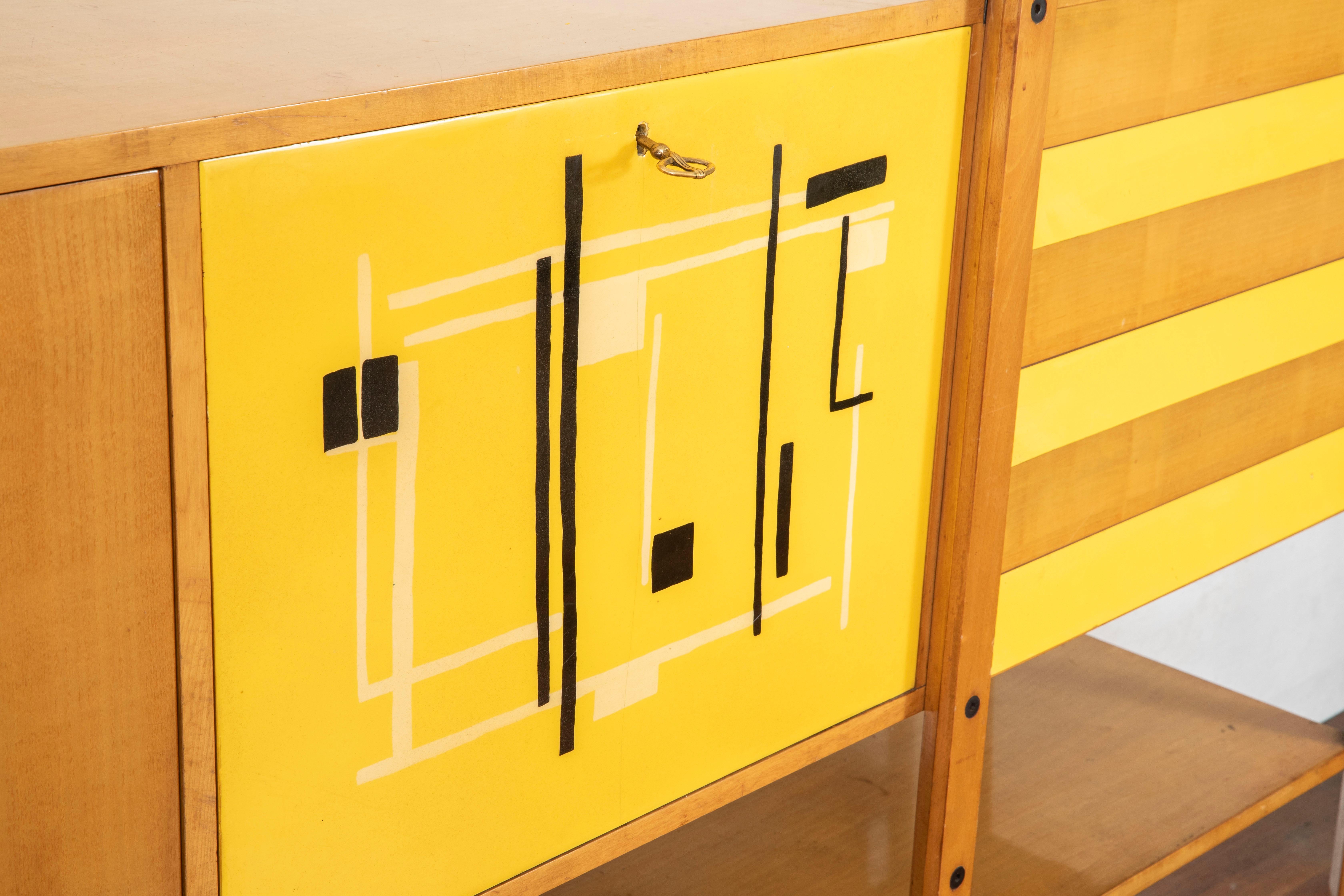 Very rare oakwood credenza designed by Roberto Aloi circa 1955, enameled steel, abstract black and yellow pattern printed plastic and glass.

Two doors conceal, two adjustable shelves and three drawers storage compartment.
