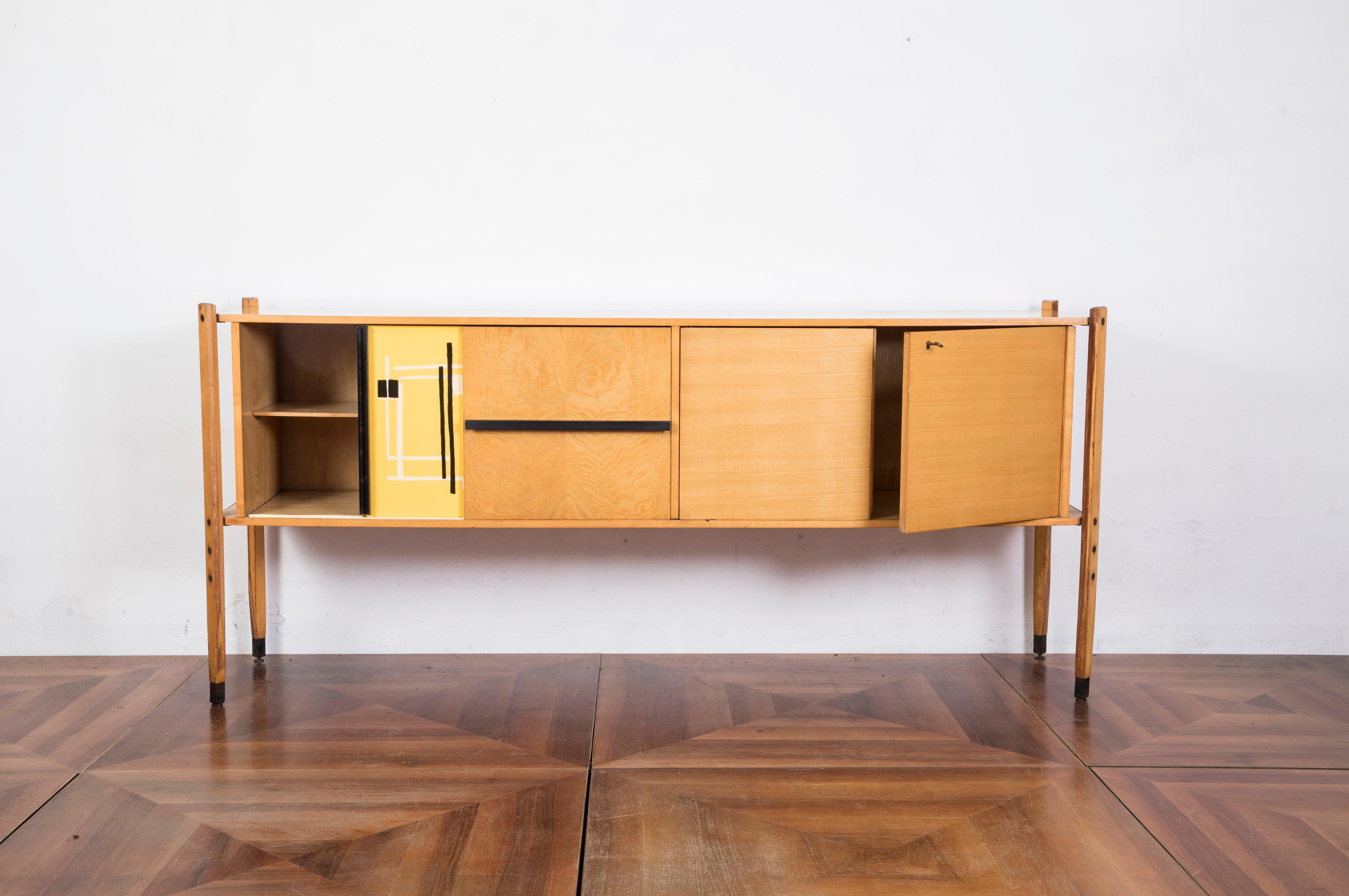 Very rare oakwood credenza designed by Roberto Aloi circa 1955, enameled steel, abstract black and yellow pattern printed plastic and glass.

Two sliding doors conceal, two adjustable shelves and two doors conceal storage compartment.