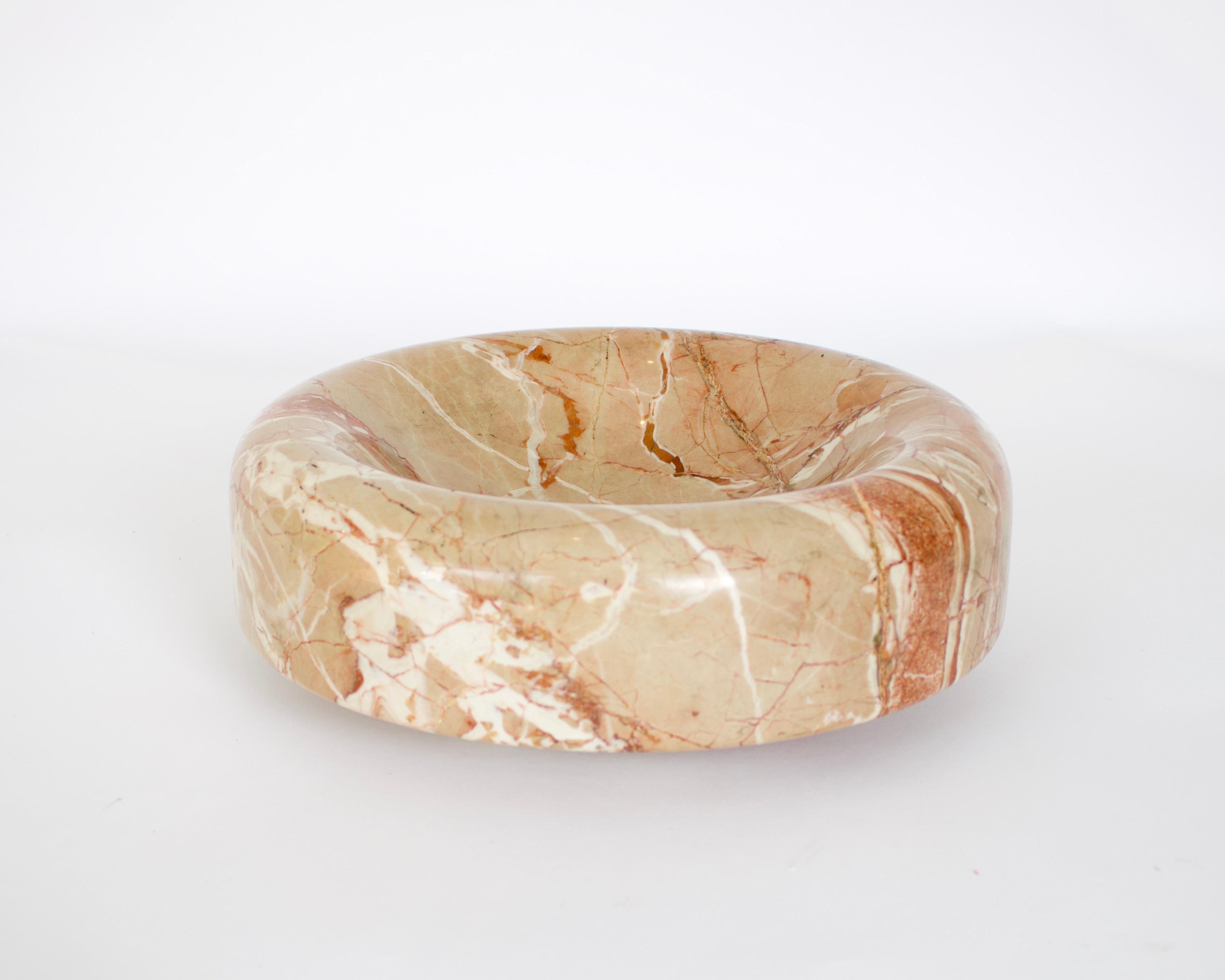 Bowl, dish or centerpiece in pale peach marble designed by Roberto Arioli for Gabbianelli in 1969. Cleverly carved, the centerpiece has a concave recess on the top, with the sides which slope downwards and below to create a single circular