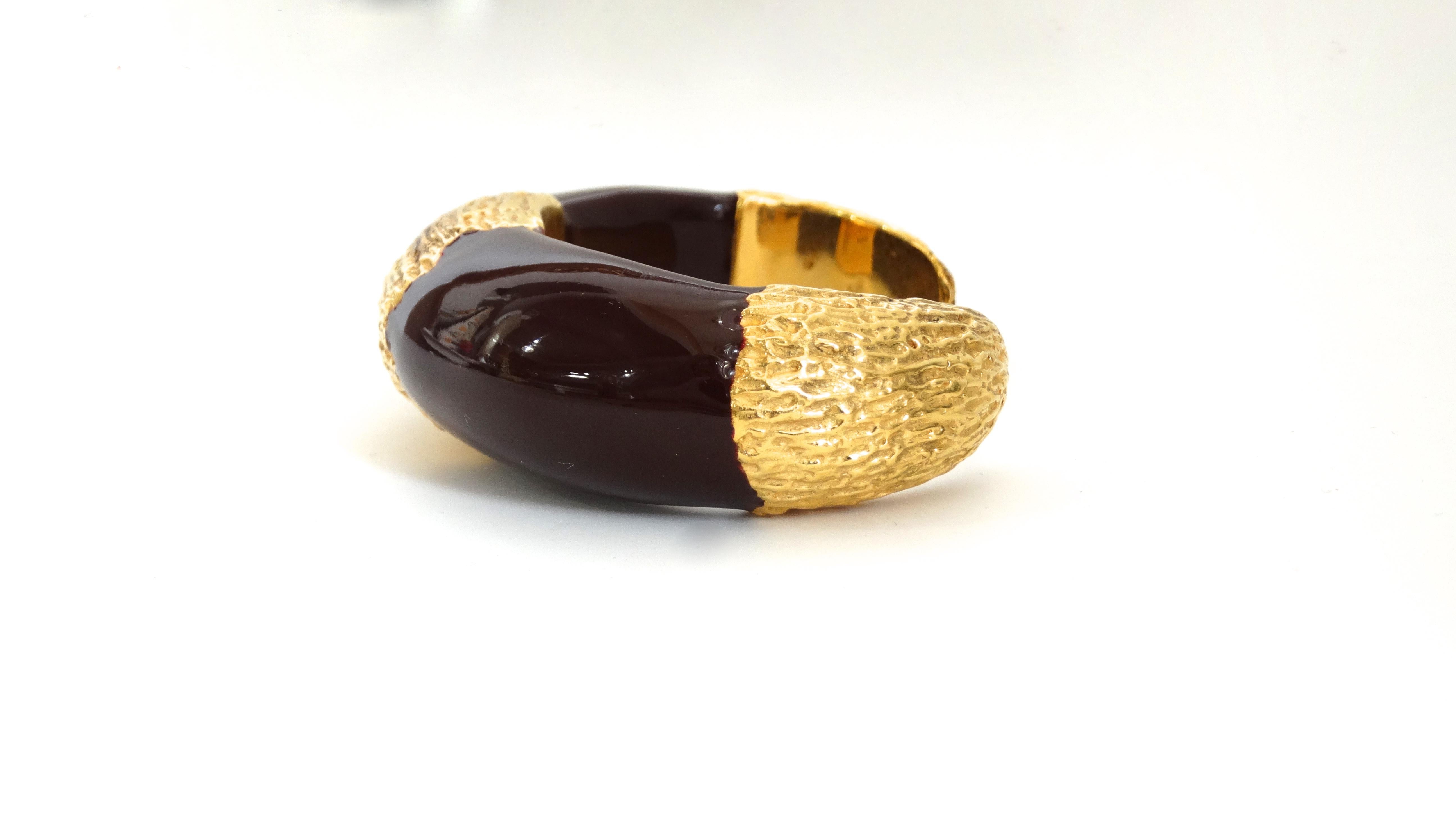 Spice up your bracelet game with this Roberto Cavalli cuff! Circa 1990s to early 2000s, this cuff is crafted from ceramic and finished in a deep burgundy color. Includes gold plated textured metal at the center and both ends. Perfect to put on with