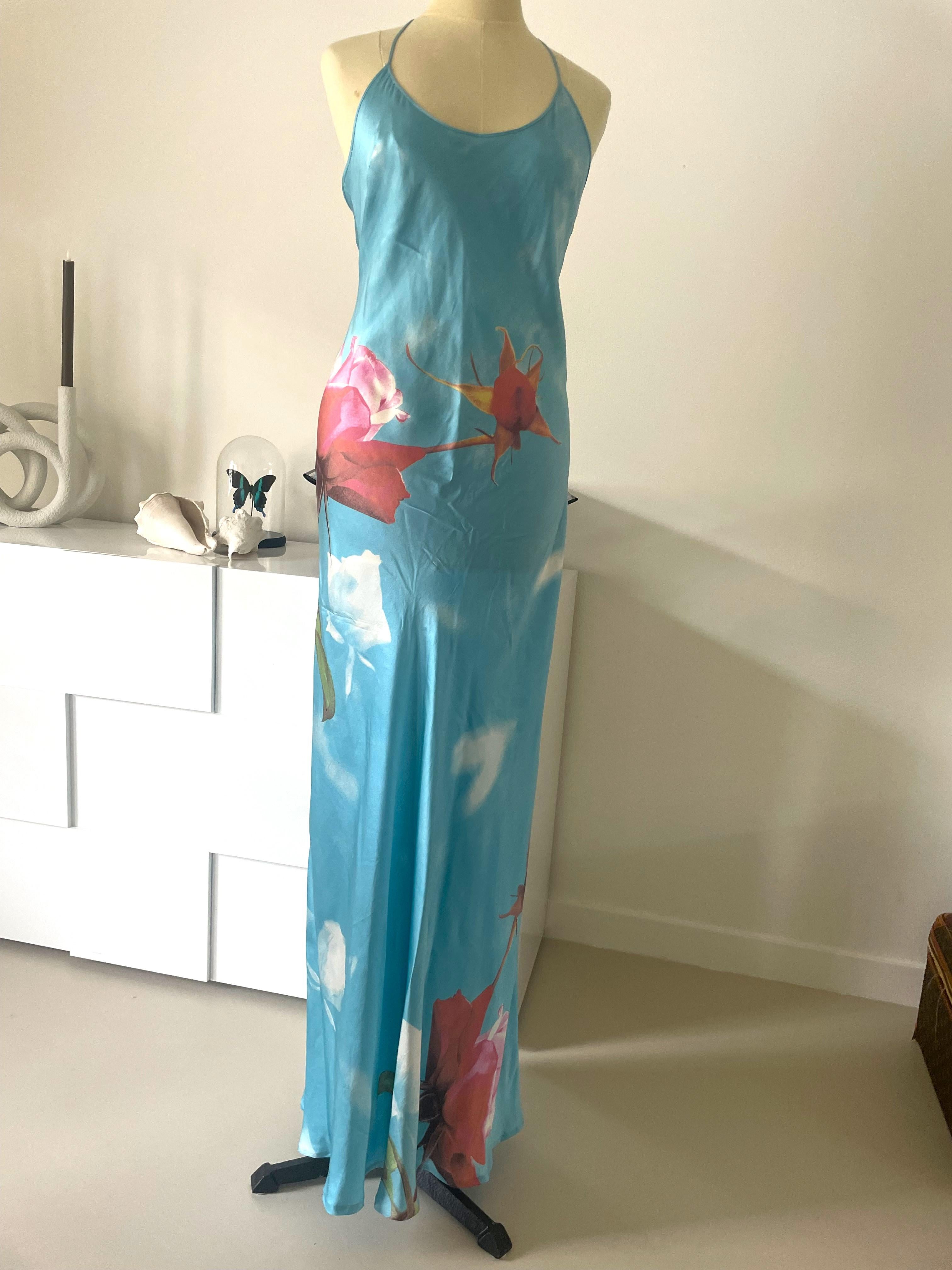 Estoy encantada de presentarte un vestido sexy vintage azul de Roberto Cavalli. Esta exquisita pieza luce un decorativo estampado floral drapeado en el busto, sostenido por tirantes finos que crean una silueta sin espalda. 
Absolutamente precioso es