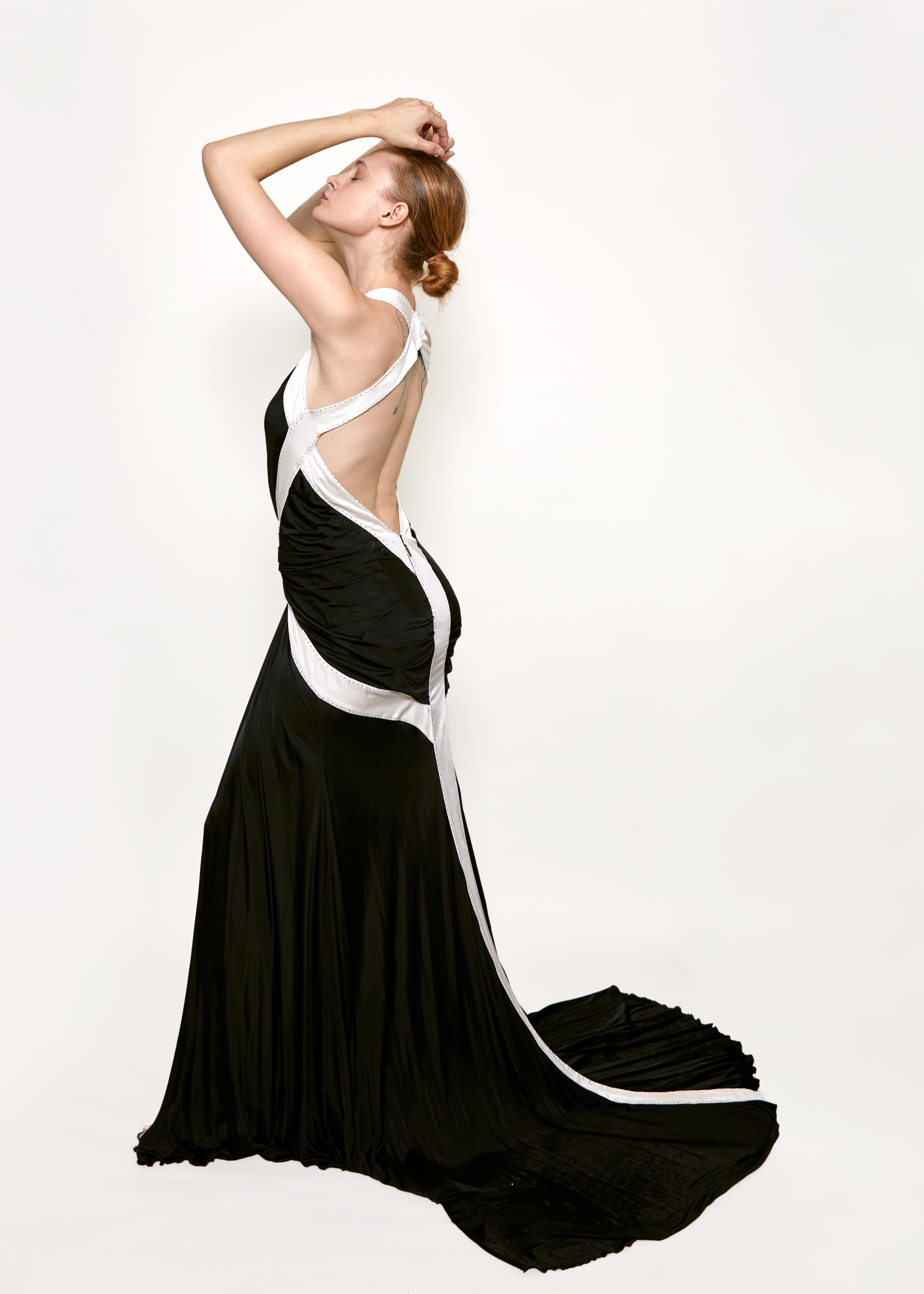 Indulge in pure elegance with Roberto Cavalli's 2008 Black/White Low Back Gown. This sophisticated gown boasts a deep plunge V-neckline and geometric color blocking, creating a stunning and exclusive look. The low back and extended train adds a