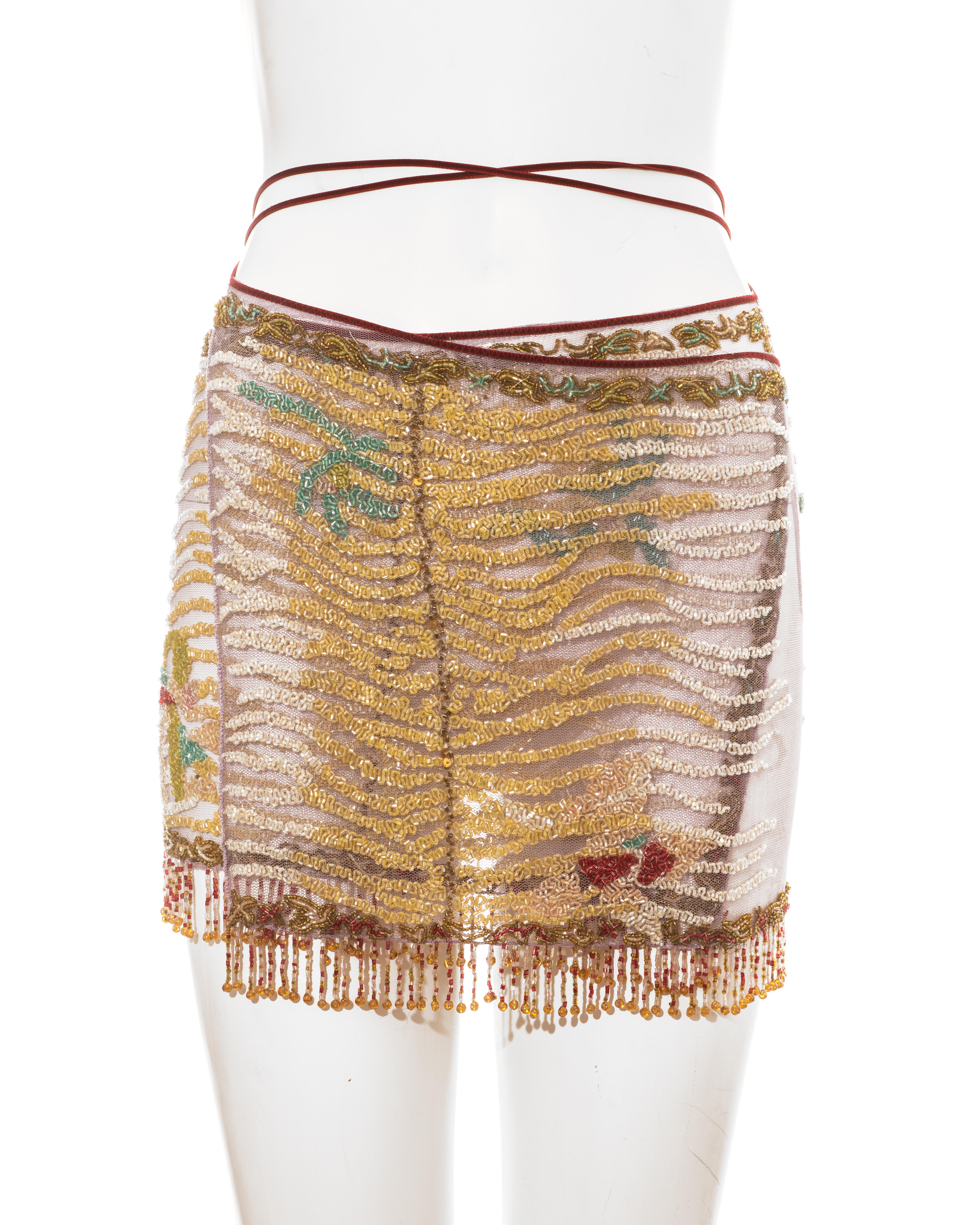 Roberto Cavalli, minigonna a portafoglio da sera impreziosita da perline multicolore con chiusura a cordoncino in velluto rosso e bordo a frange. 

Primavera-Estate 2000