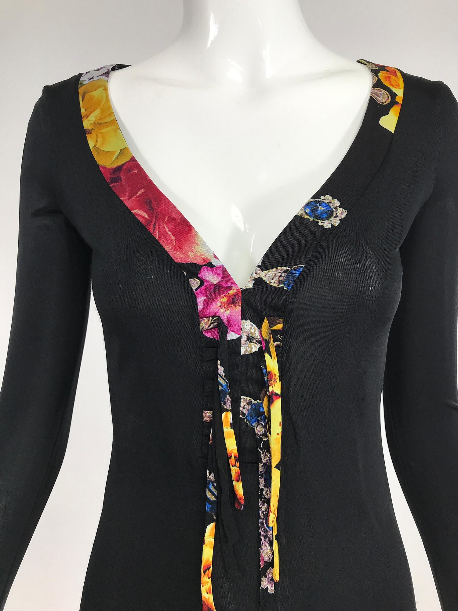 Roberto Cavalli black jersey V plunge laced front top, long sleeve top. Low V neckline trimmed with floral fabric and floral ties, the long sleeves have bell ruffle cuffs with floral ties. The top is fitted and approximately hip length. Rayon