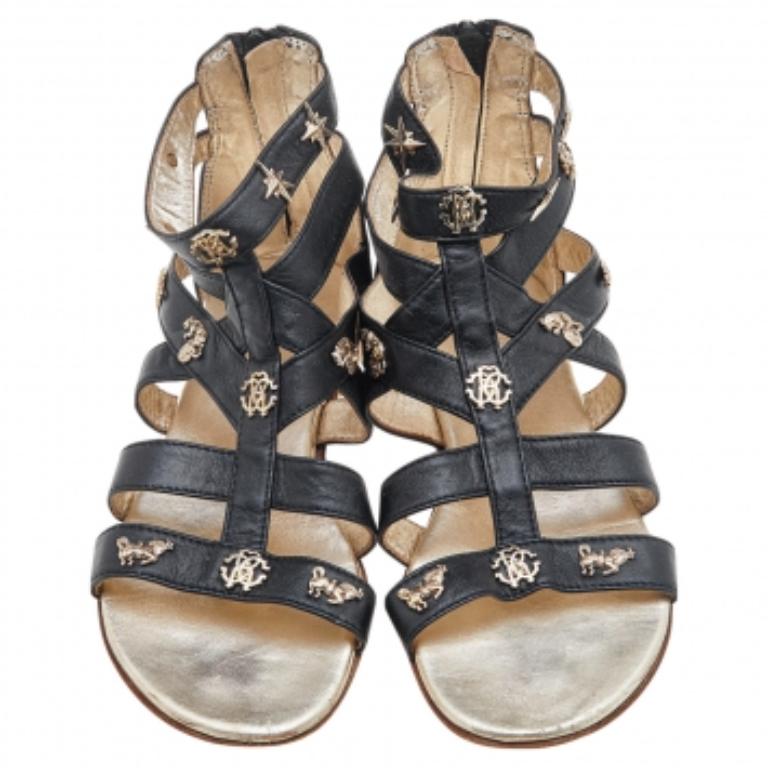 Mit diesen fabelhaften Sandalen aus dem Hause Roberto Cavalli gehen Sie jeden Schritt mit Eleganz. Sie sind aus schwarzem Leder gefertigt und mit Verzierungen auf dem Obermaterial versehen. Sie weisen goldfarbene Beschläge auf. Kombinieren Sie sie
