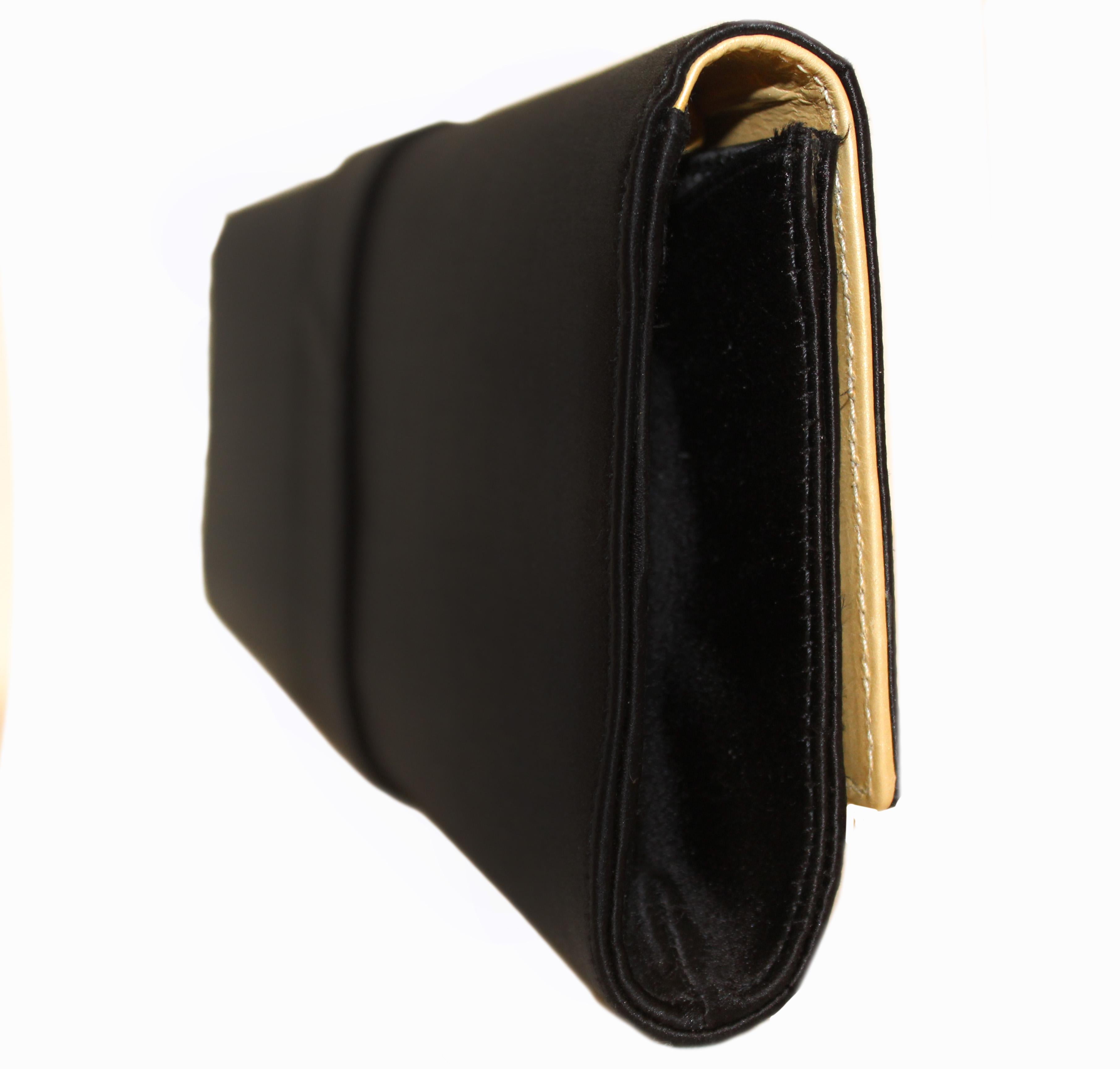 Roberto Cavalli black satin clutch bag is a classic.  Presenting this black satin structured clutch from Roberto Cavalli featuring a gold-tone chain shoulder strap, a fold-over top with magnetic closure, a front snake  plaque, multiple interior