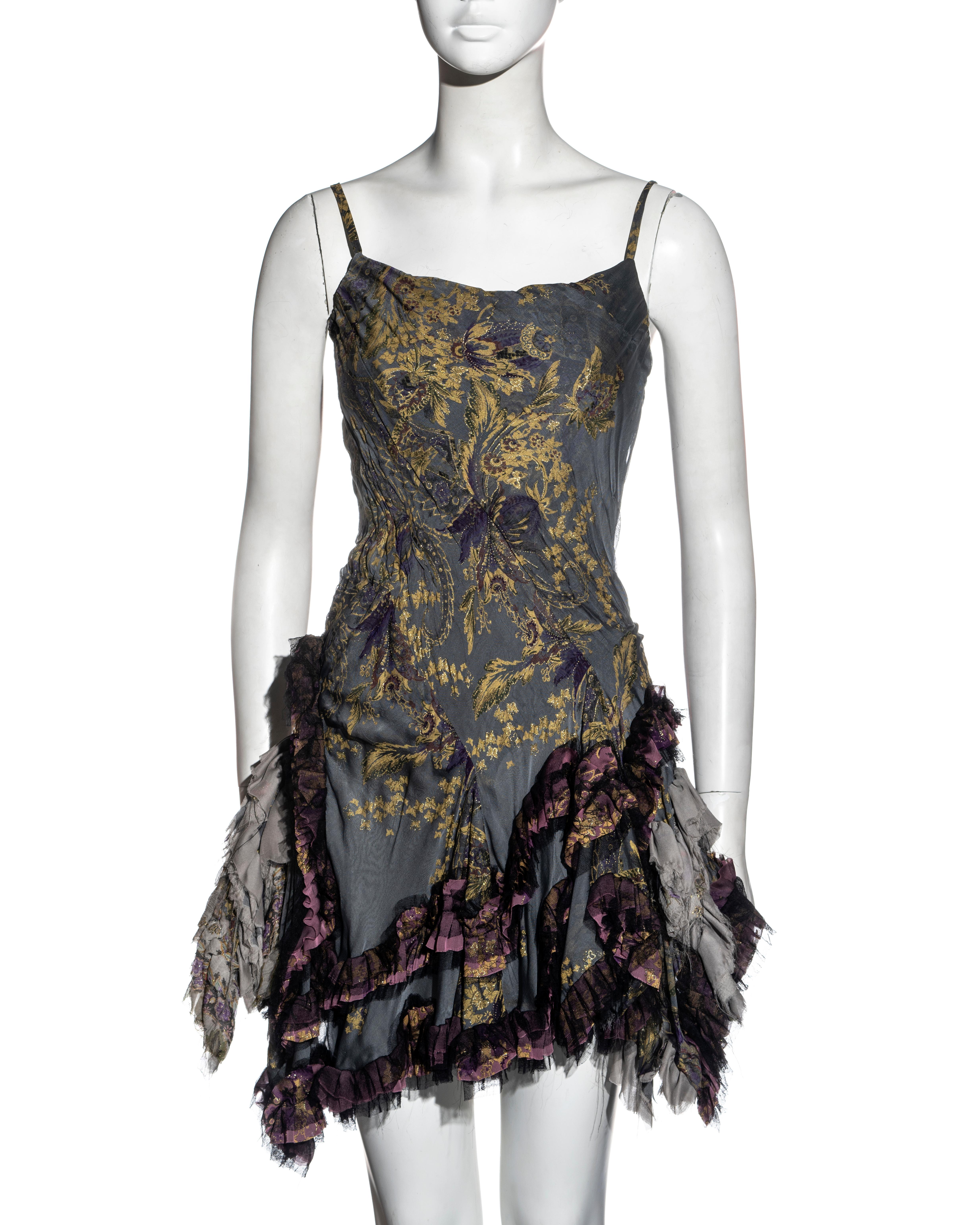 ▪ Roberto Cavalli silk corseted mini dress
▪ Blue-grey and metallic gold brocade printed silk 
▪ Corseted bodice with asymmetric ruching 
▪ Ruffled mini skirt with frayed hem 
▪ Corset lace-up fastening at the back 
▪ Size Small
▪ Fall-Winter 2004
▪