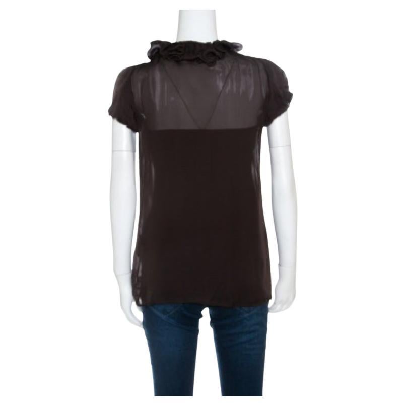 Il est temps d'être glamour avec ce chemisier marron de Cavalli. Cette blouse est réalisée en 100 % soie et présente une encolure volantée. Il se ferme par des boutons sur le devant, présente des manches courtes bordées de volants et un dos