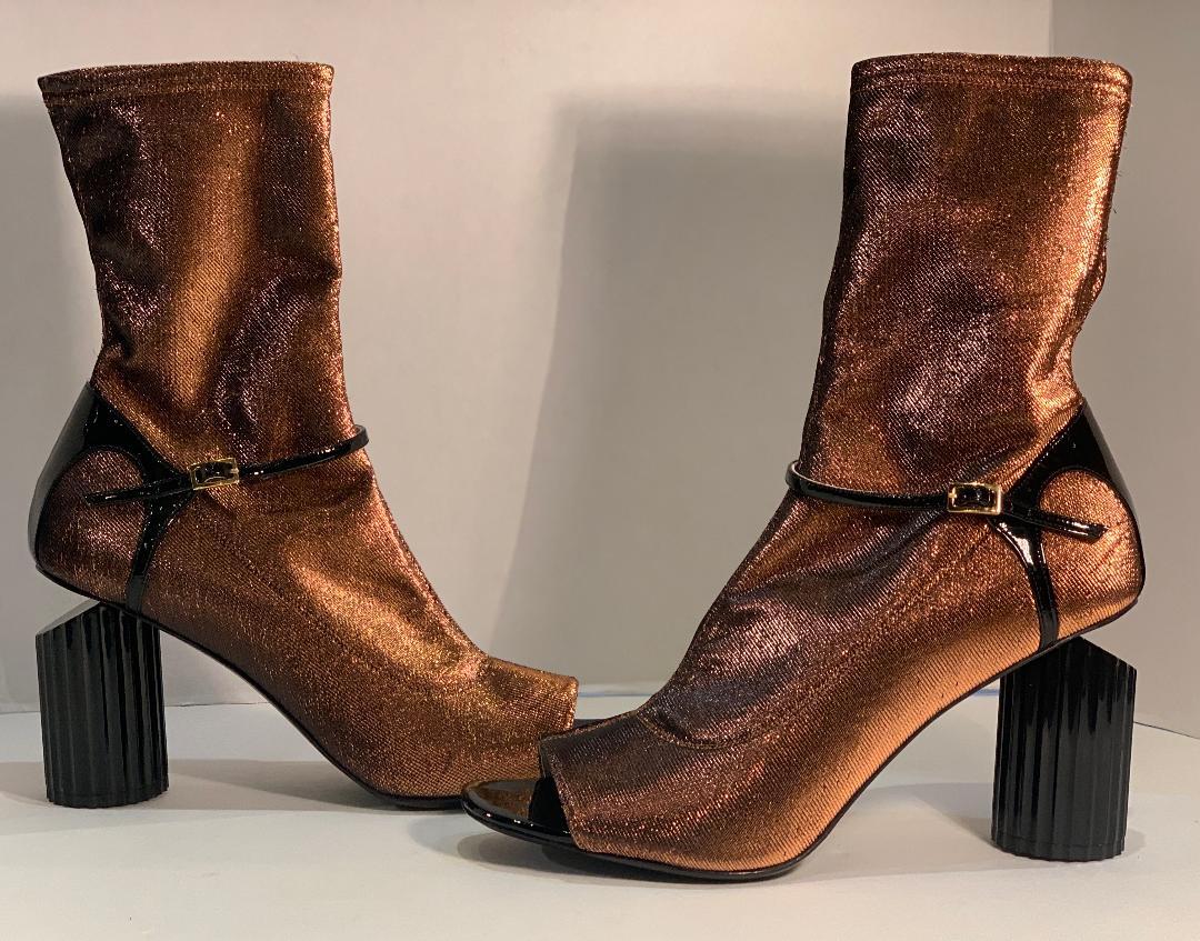 Very avant garde, Italian luxury brand, Roberto Cavalli, size 41 bootie shoes.  These edgy shoes feature open toes, a striking copper metallic slight stretch fabric with black patent leather trim, and a unique black circular fluted 4 inch high heel.