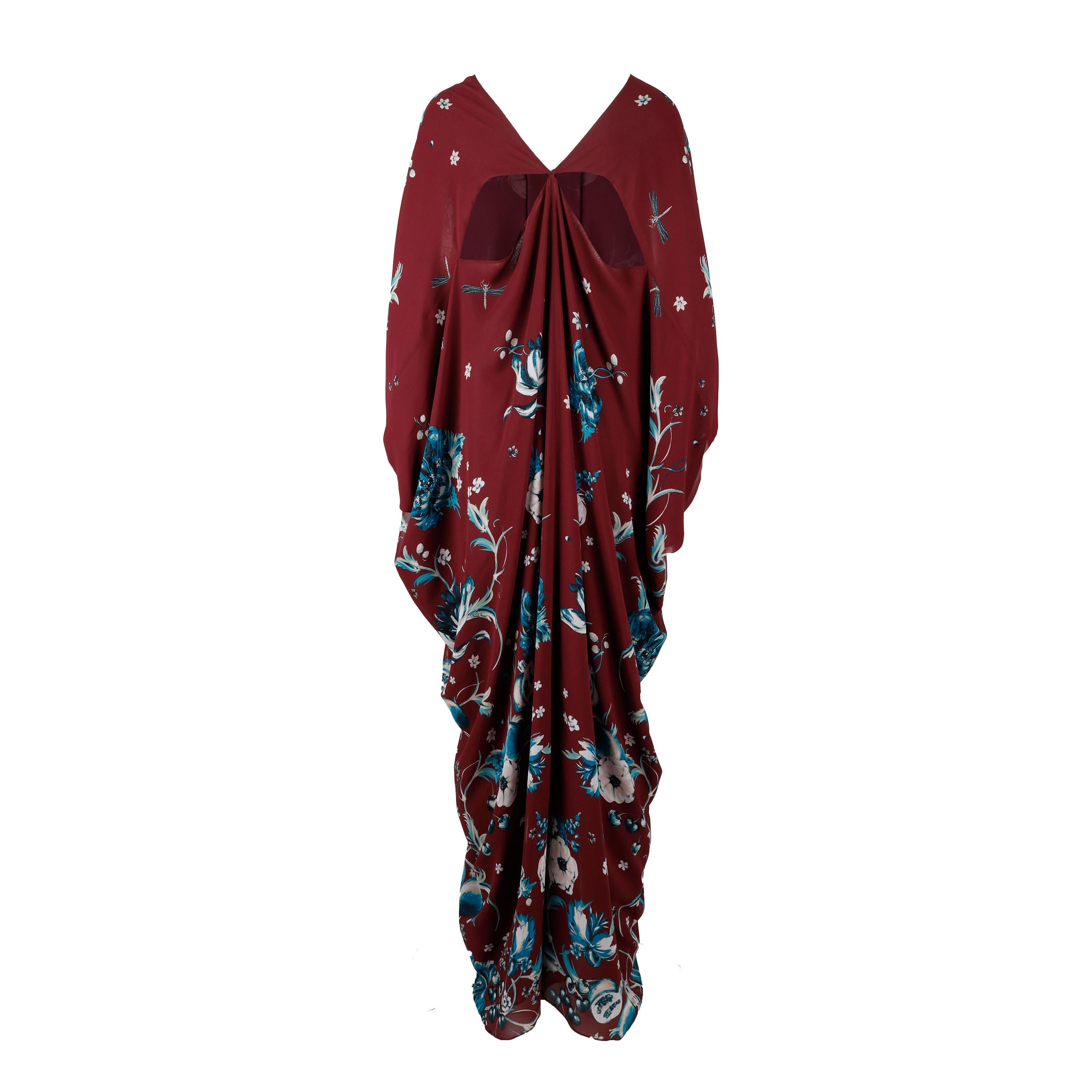 This Roberto Cavalli Silk Kaftan Dress features a beautiful floral print with turquoise accents in burgundy, set off by cutout accents. It boasts a loose kimono sleeve and a v-neck, making it the perfect summer wear.