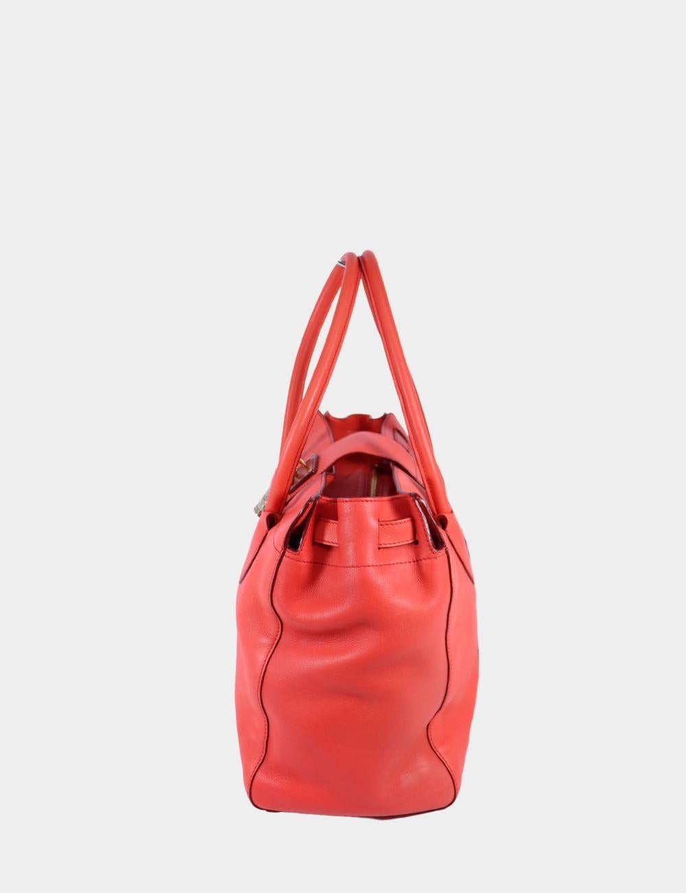 Fai colpo con questa audace e bellissima tote in pelle corallo di Roberto Cavalli. Realizzata in pelle morbida e di alta qualità, questa spaziosa tote presenta eleganti pannelli curvi, doppi manici superiori e un accento di serratura dorata sulla