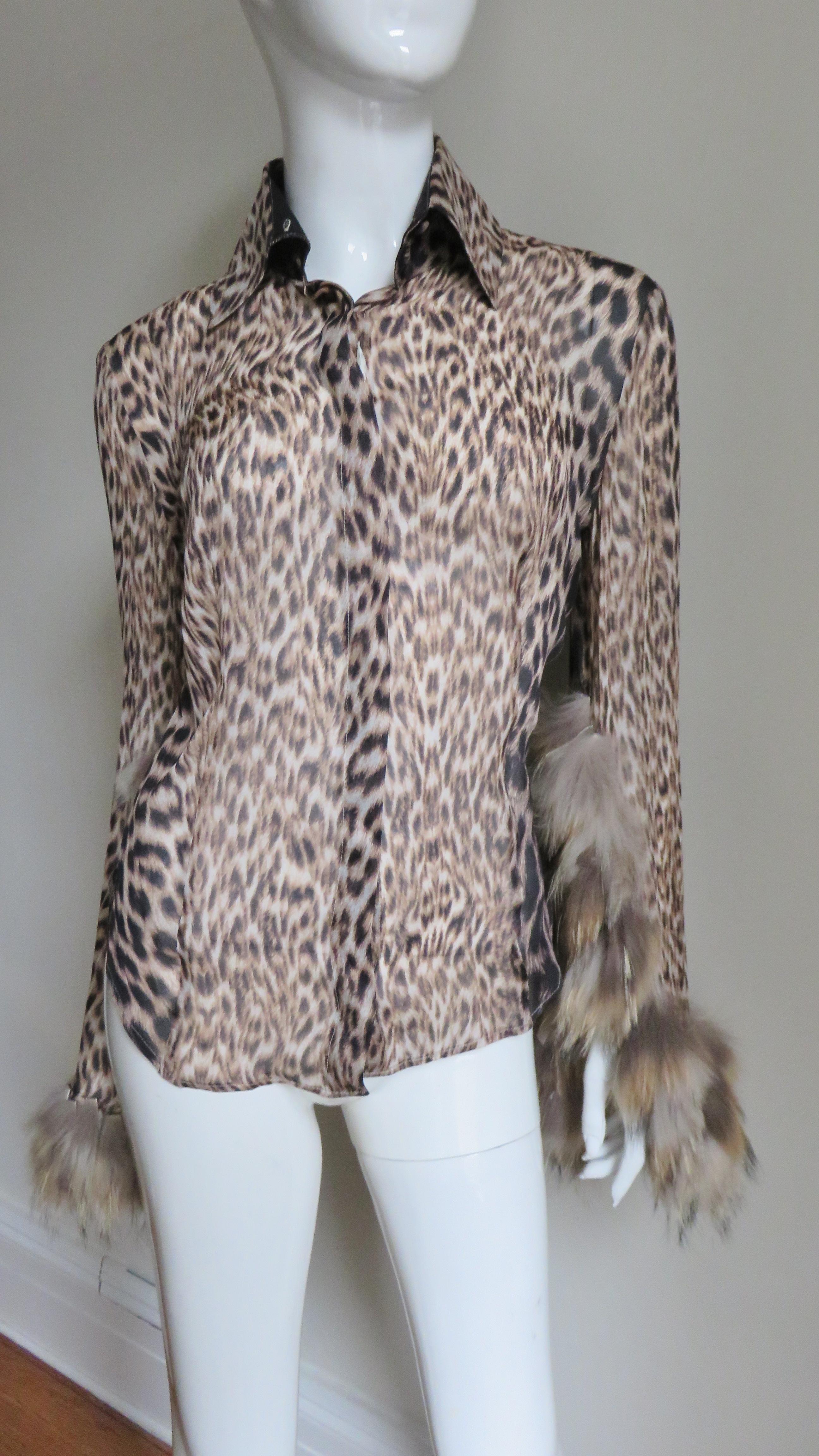 A gorgeous leopard print silk shirt, blouse by Roberto Cavalli.  It has a shirt collar and long bell sleeves highlighted with rows of small strips of fox fur at the bottom. There is a front placket hiding small self covered buttons. Stunning!
Fits