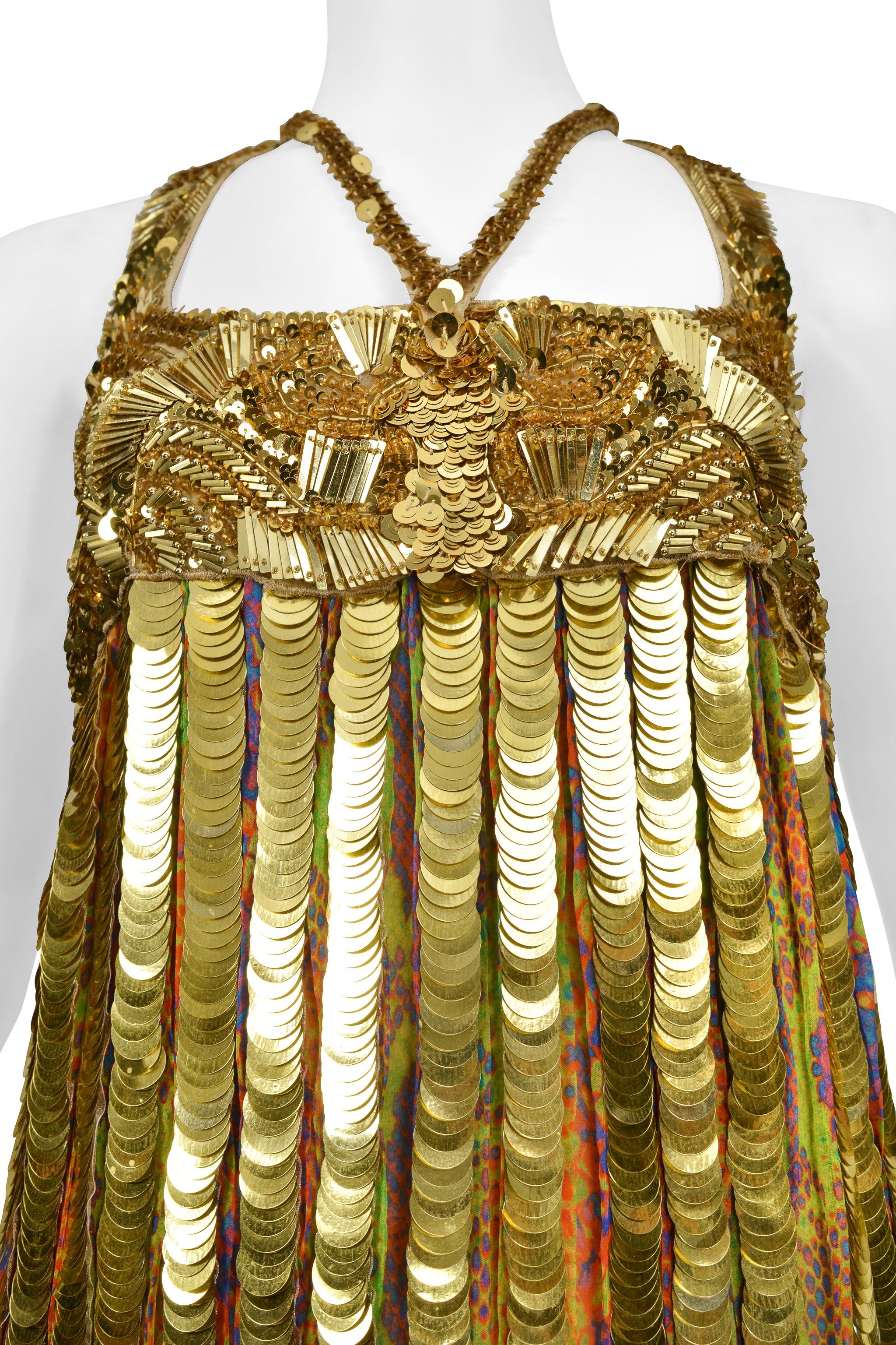 Resurrection Vintage se complace en presentar un minivestido de cóctel vintage Roberto Cavalli de estilo flapper dorado con lentejuelas y paillettes doradas, abundante pedrería en el canesú y la cintura caída, tirantes decorados, sisas profundas,