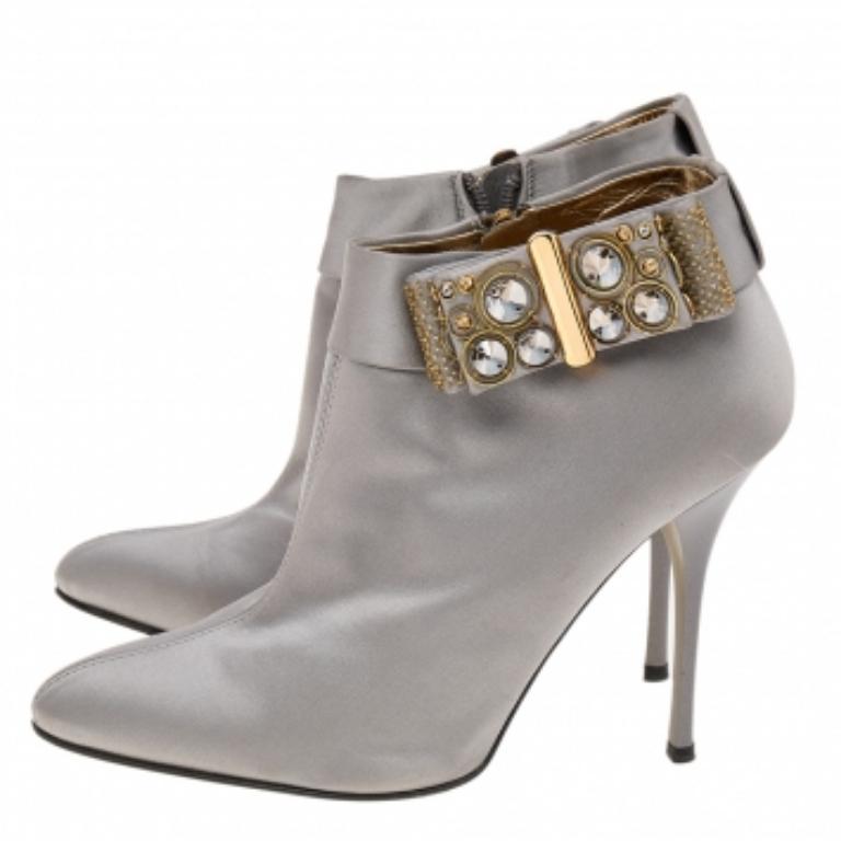 Gardez votre style étincelant et éblouissant avec ces bottes de la maison Roberto Cavalli. Elles sont fabriquées en satin gris sur l'extérieur et un délicat nœud embelli souligne leur apparence. Ils sont dotés d'orteils pointus, de talons fins et