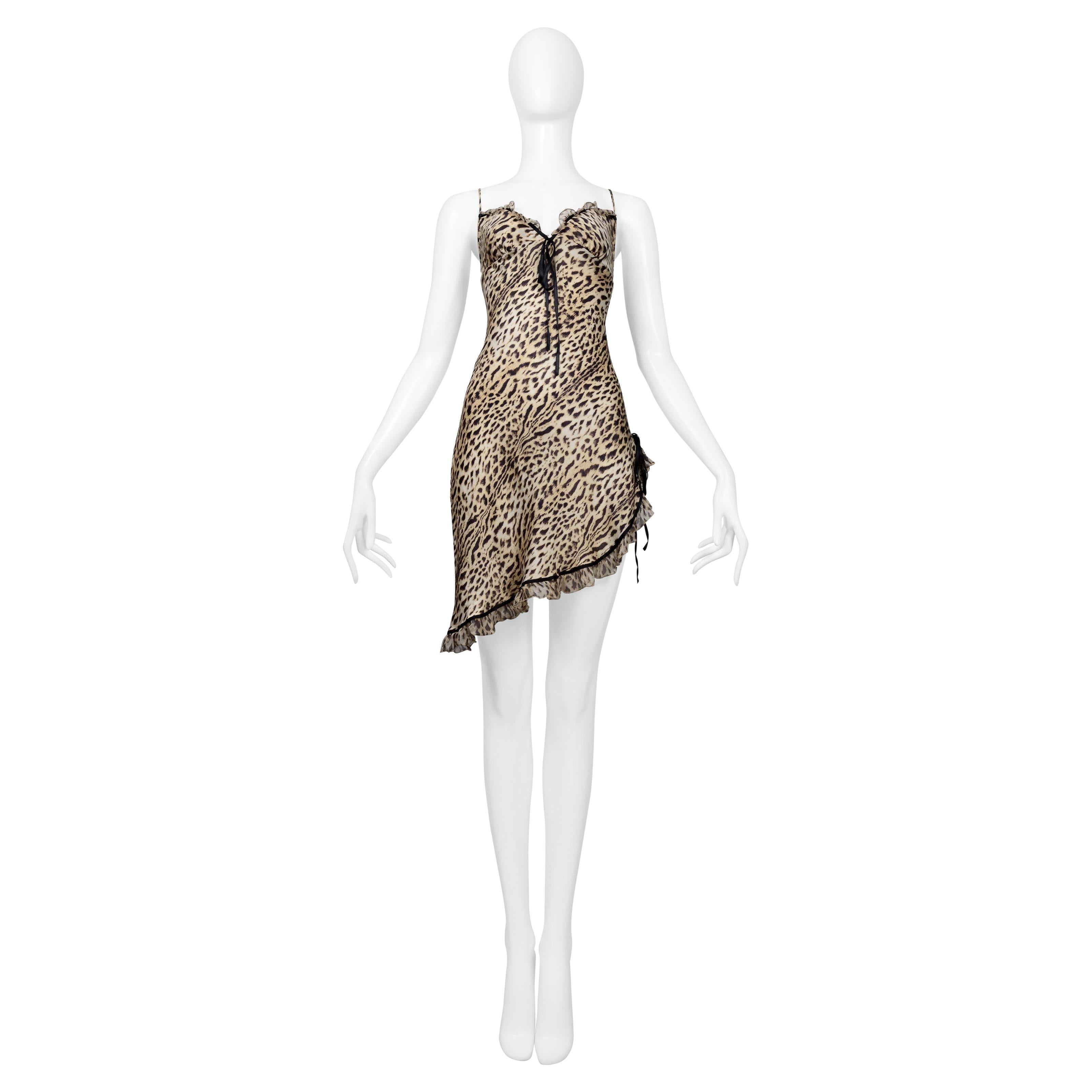 Resurrection Vintage is excited to offer a vintage Roberto Cavalli mini leopard silk slip dress featuring an asymmetrical hem at bottom with ruffle accents, high slit up right hip with black ribbon bow detail, sweetheart neckline with ruffle accents