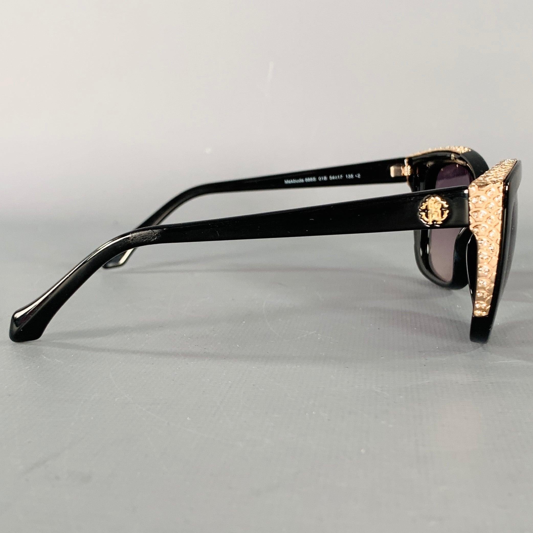 ROBERTO CAVALLI sunglasses
in a black acetate featuring
a cat eye style, and rose gold tone metal temple accents with rhinestones. Made in Italy.Very Good Pre-Owned Condition.  

Marked:   888S 01B  

Measurements: 
  Frame Width: 13.5 cm.Frame