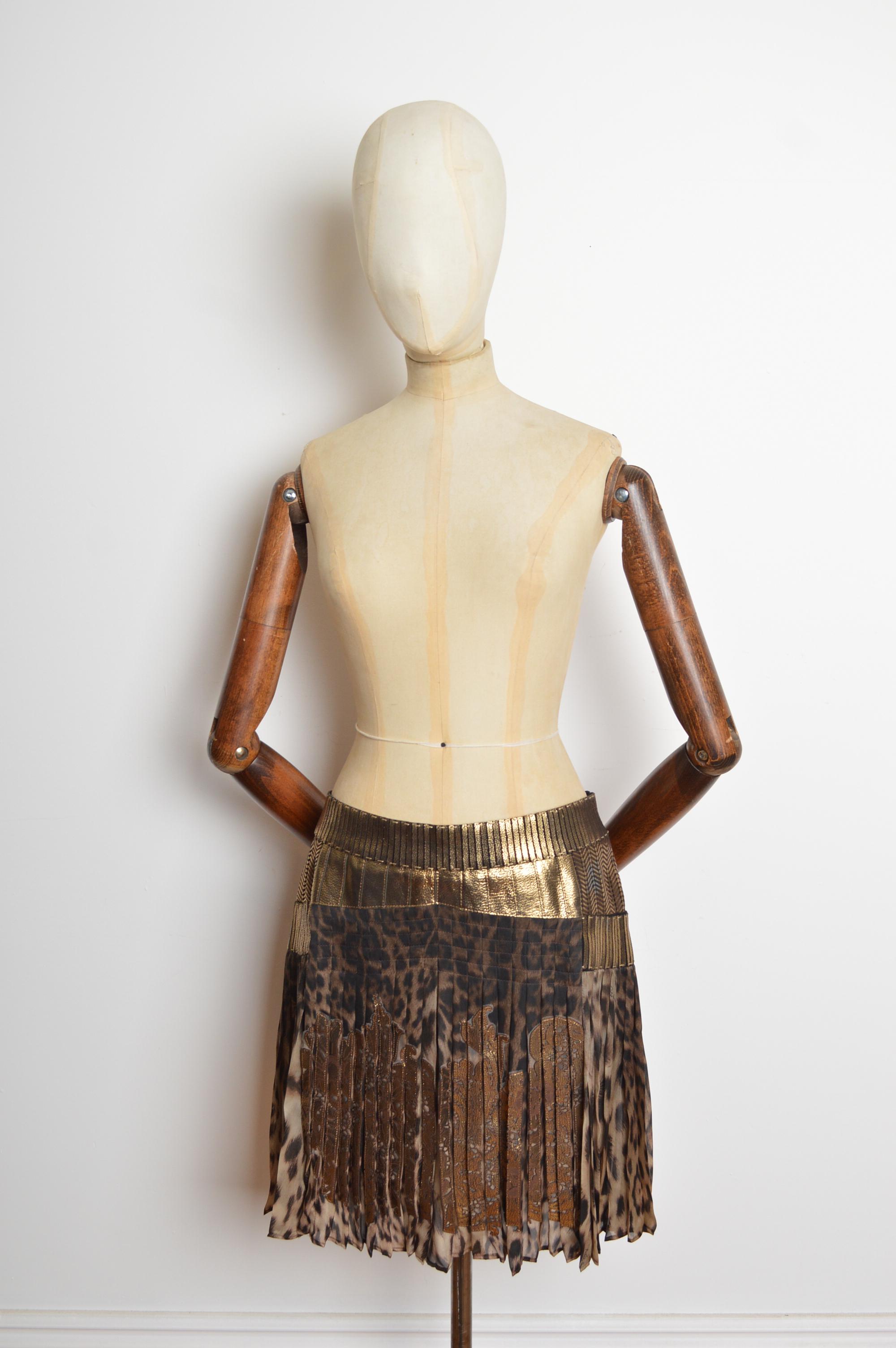 Ein prächtiger Roberto Cavalli Vintage-Minirock aus reiner Seide und goldenem Leder. Das Oberteil aus Seide mit Leopardenmuster ist in Falten gelegt und mit einer kunstvollen Lamé-Lederverzierung versehen. 
GEFERTIGT IN ITALIEN.
Der Rock kann mit