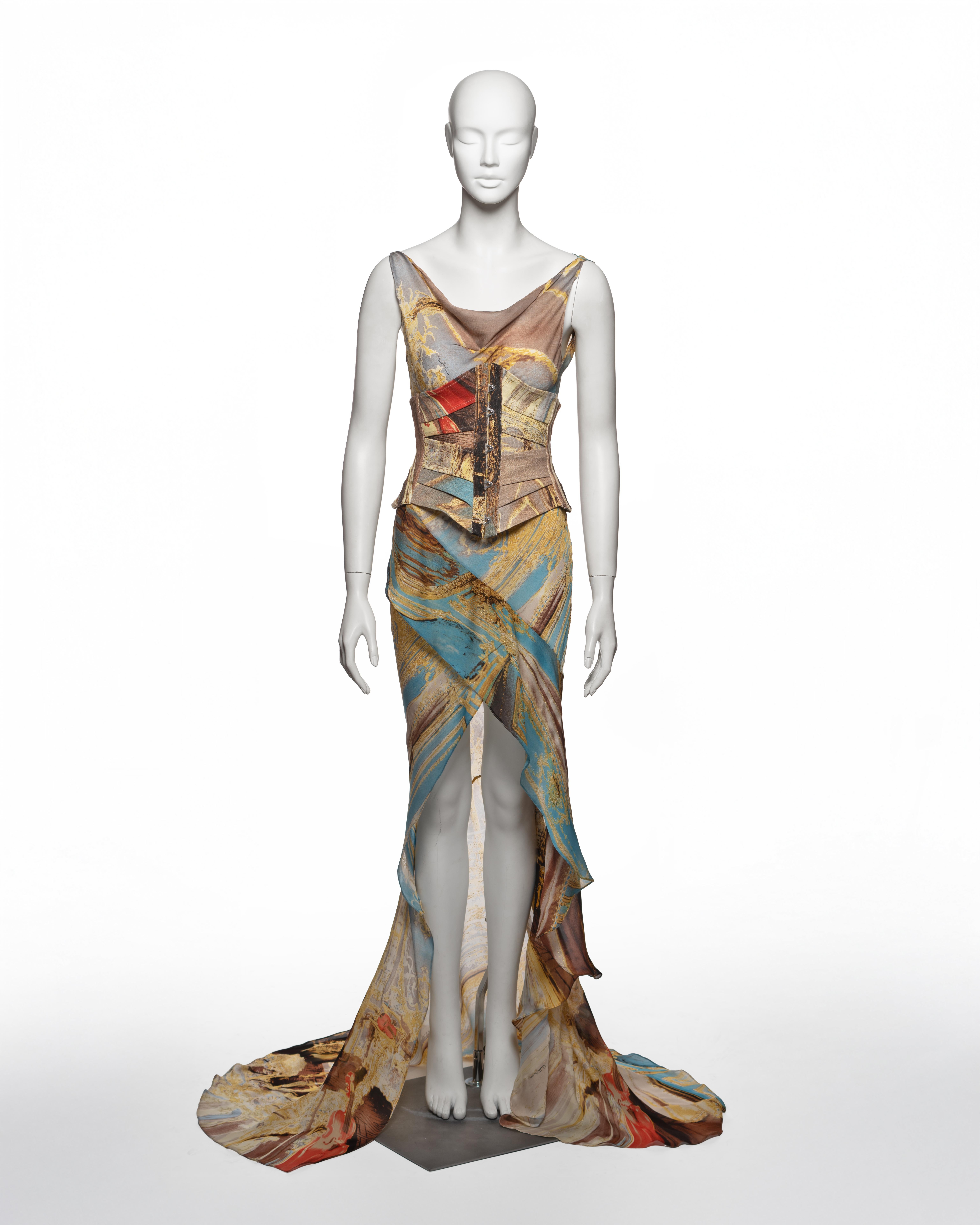 This Roberto Cavalli runway look from the Spring-Summer 2003 collection comprises a digitally printed silk evening dress and a structured cotton corset. The full-length bias-cut dress is constructed in a fluid draped silhouette with a cowl neckline