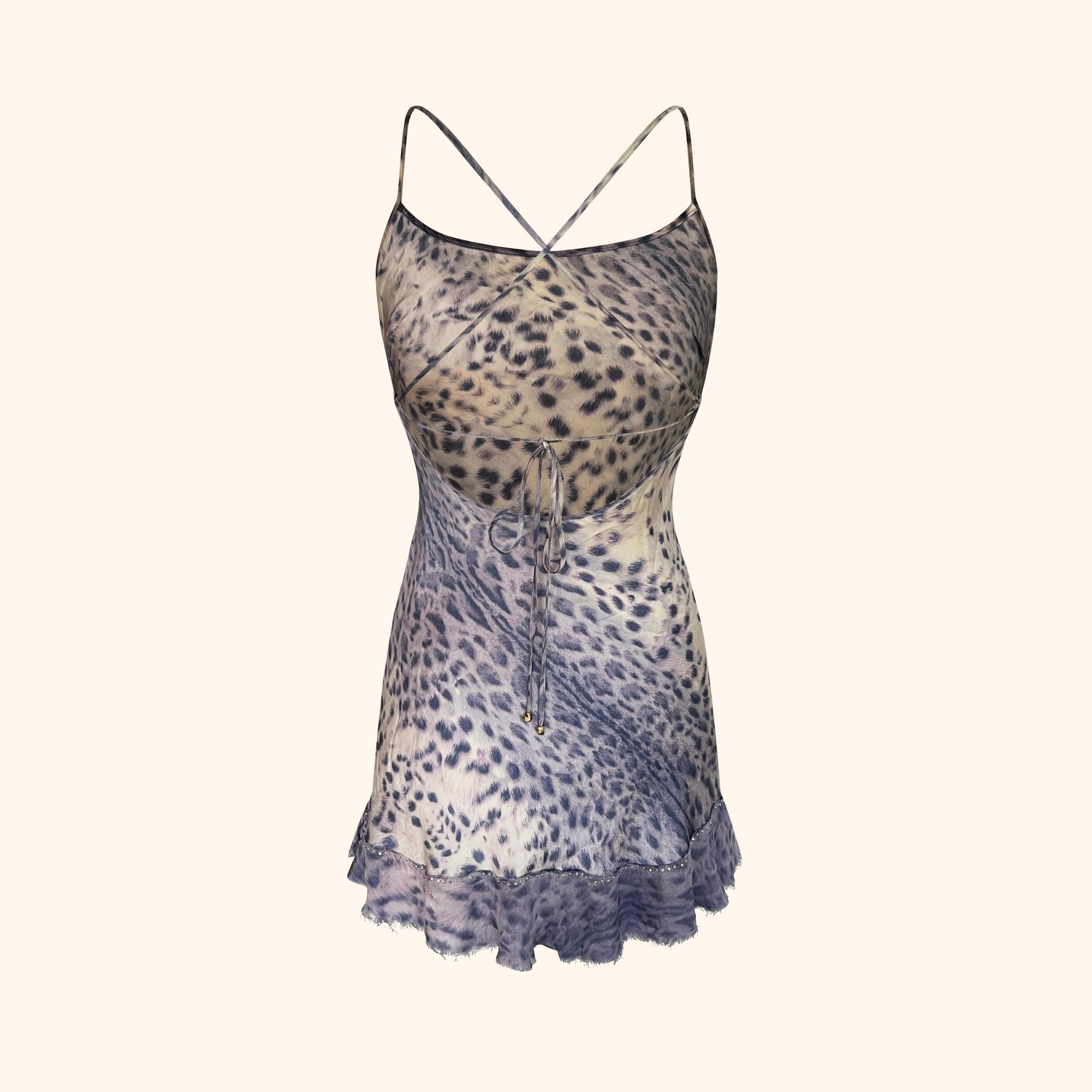 Iconico abito in seta viola leopardato di Cavalli della collezione Primavera/Estate 2000.
Presenta una silhouette aderente con spalline incrociate sulla schiena, un dettaglio di cravatta con minuteria RC dorata e un orlo increspato rifinito con