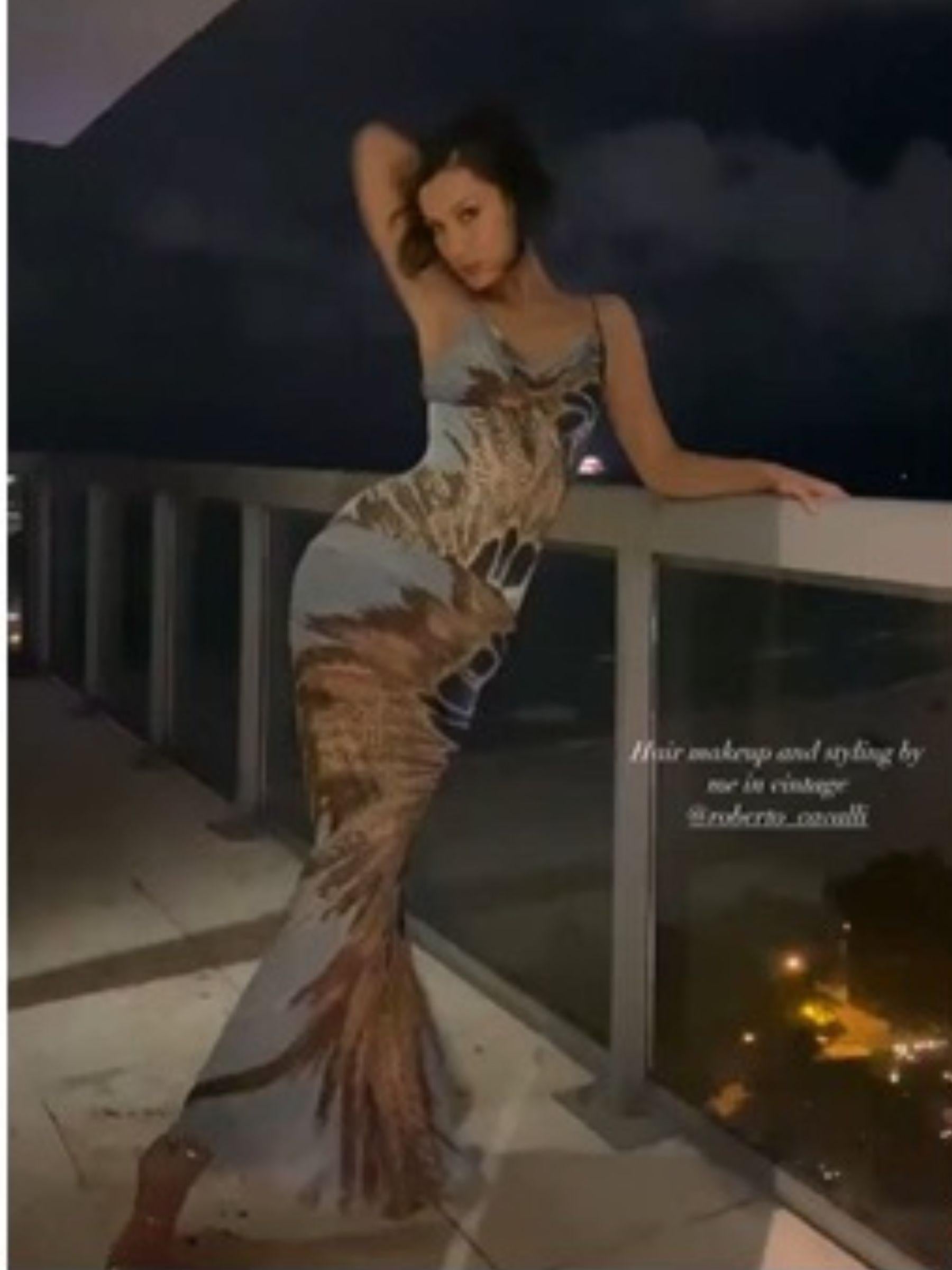 Questo maxi abito mozzafiato è realizzato in lussuosa seta e mette in mostra la maestria di Roberto Cavalli nel creare stampe dinamiche. 
Il suo accattivante design caleidoscopico nei toni della terra del marrone, del blu e del crema crea un impatto