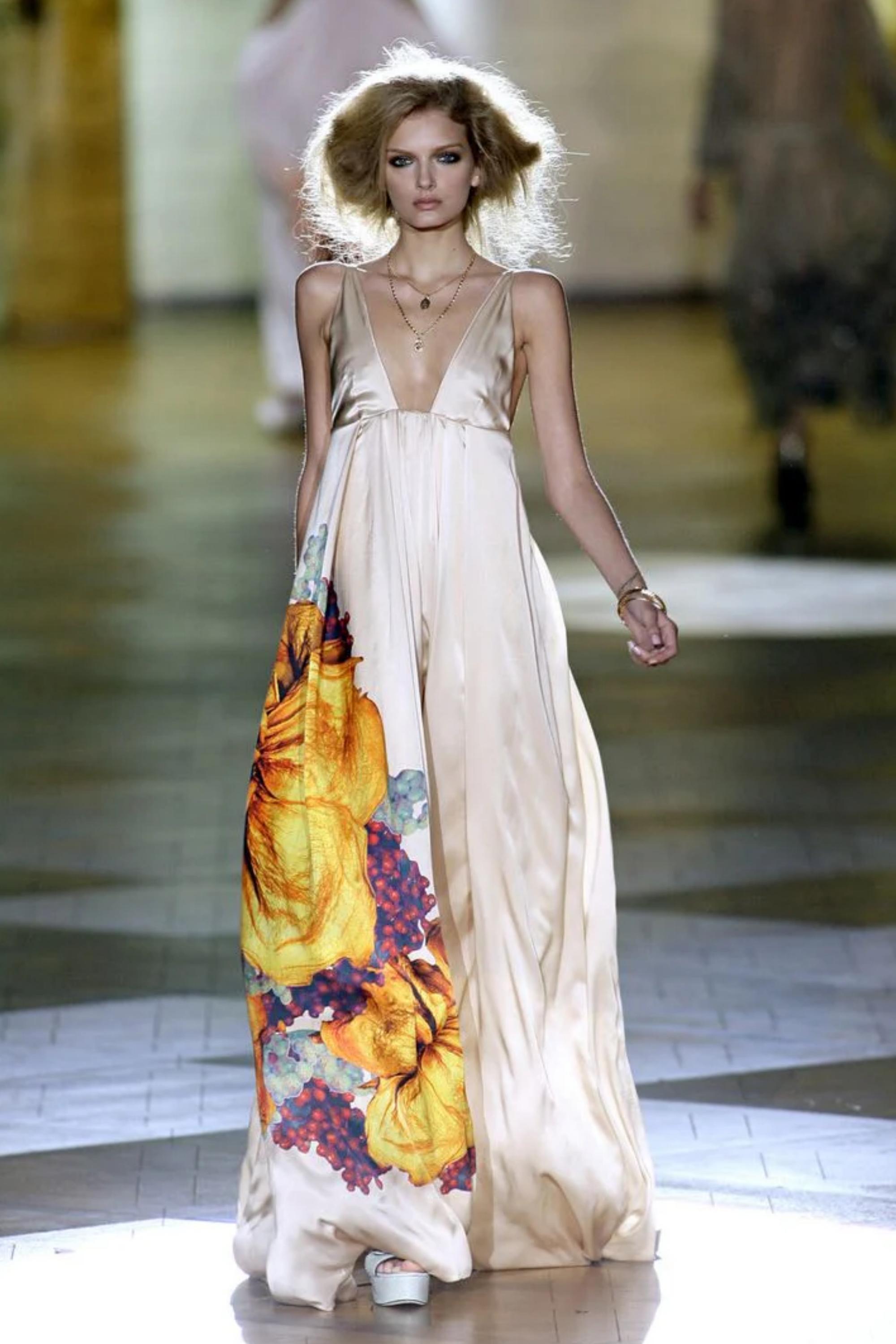 Fai un'affermazione grandiosa con questo splendido abito di Roberto Cavalli della collezione primavera estate 200857005. Il lussuoso tessuto avorio è ornato da audaci stampe floreali, che mescolano gialli vivaci e viola ricchi per un contrasto