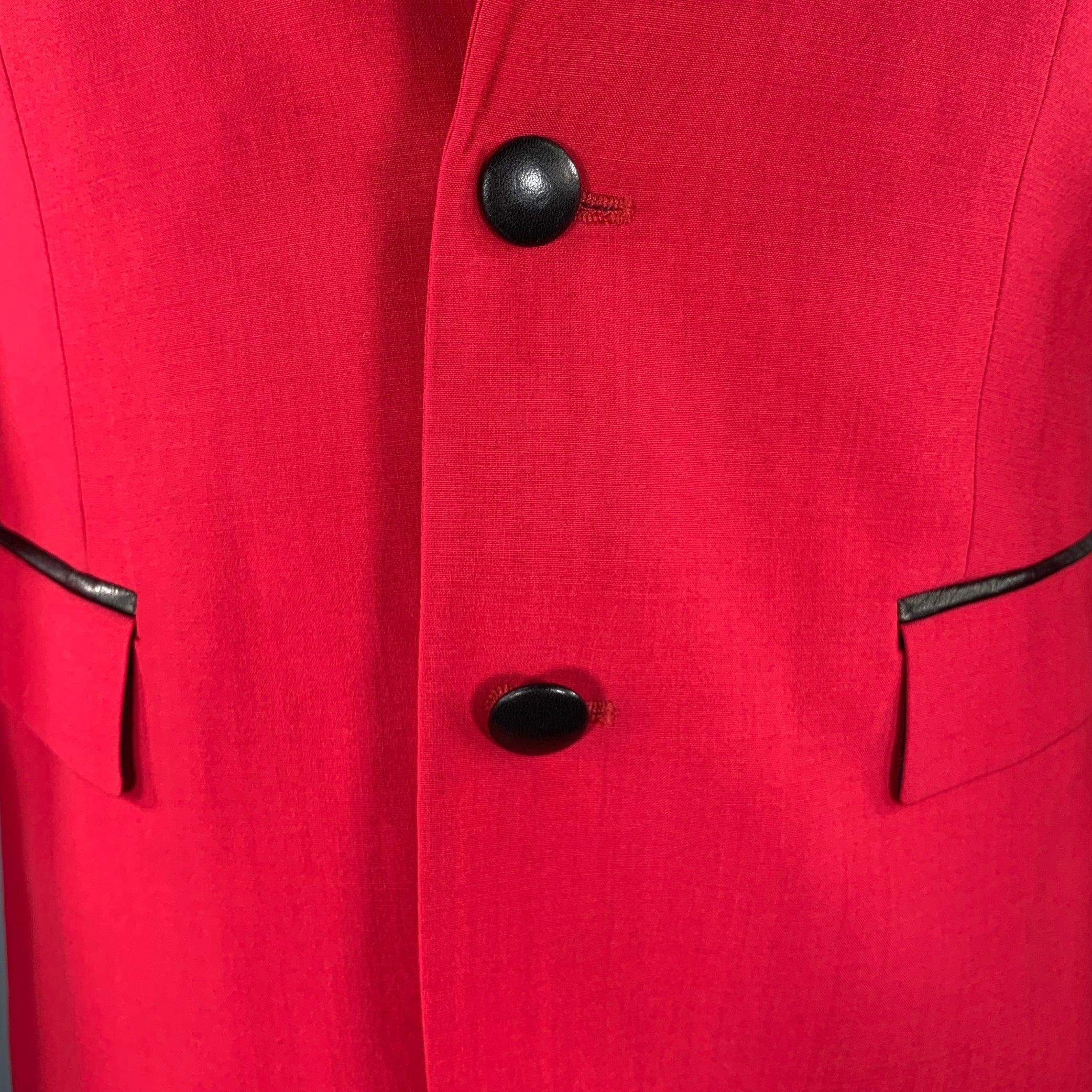 Manteau de sport ROBERT Cavalli
en laine mélangée rouge framboise, avec des bordures et des boutons contrastés en cuir d'agneau noir, un revers échancré, un dos sans aération et une double fermeture boutonnée. Fabriqué en Italie. Nouveau avec