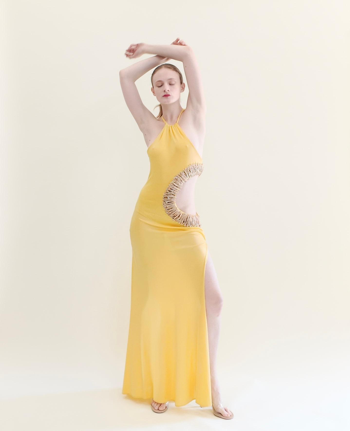 Experience the timeless and iconic style of Roberto Cavalli with this stunning archival piece from the Spring 2005 collection. This yellow gown features intricate gold threading and chunky jeweled details, accented by a high split and halter neck