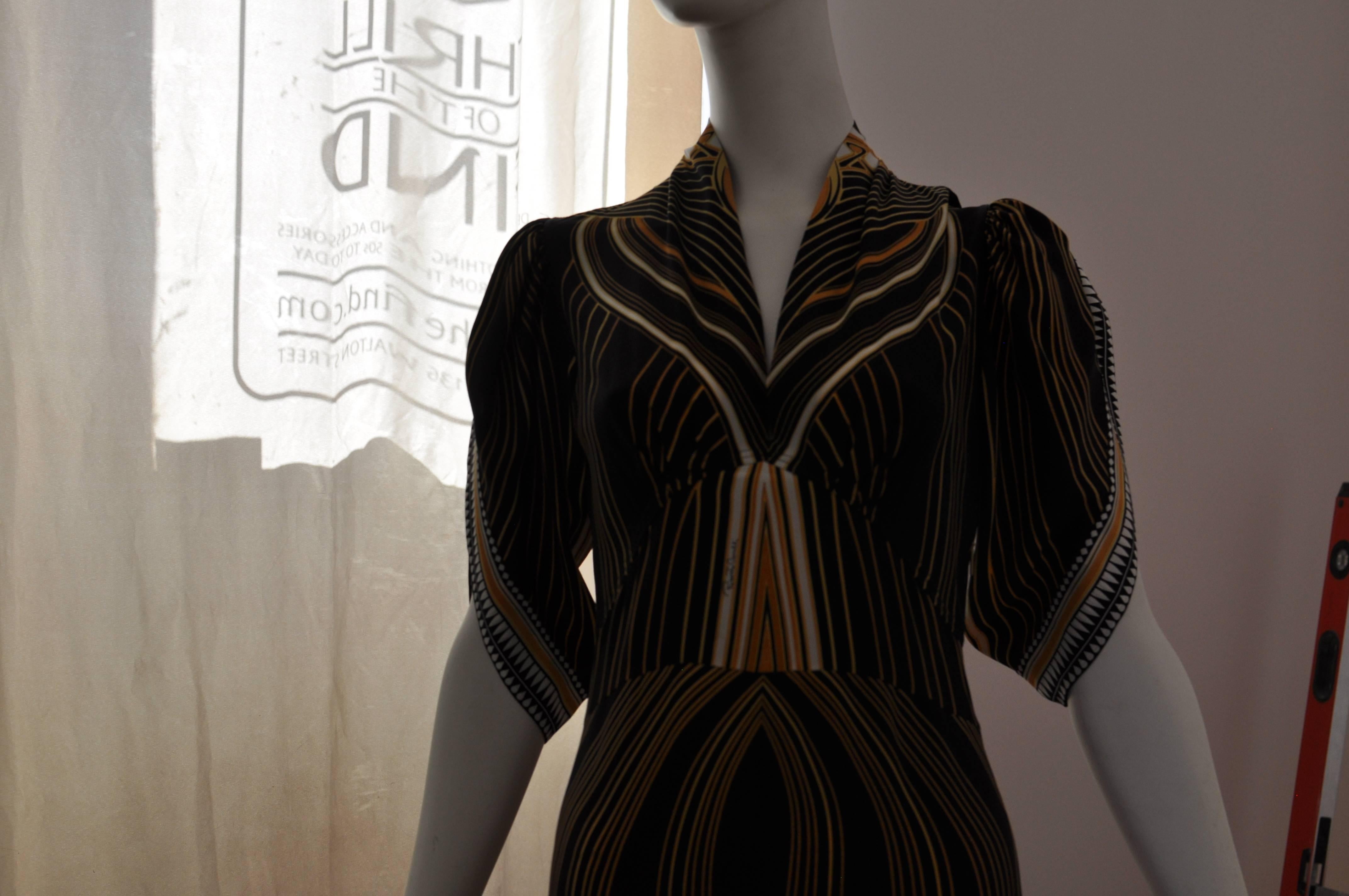Wonderful peacock and stripe design which was shown in different styles in the 2007 collection. Beautiful almost shawl neckline; lovely detailed sleeves; flowing skirt ruffled detail at the back neck, and V-band under the bust.
This is a dress which