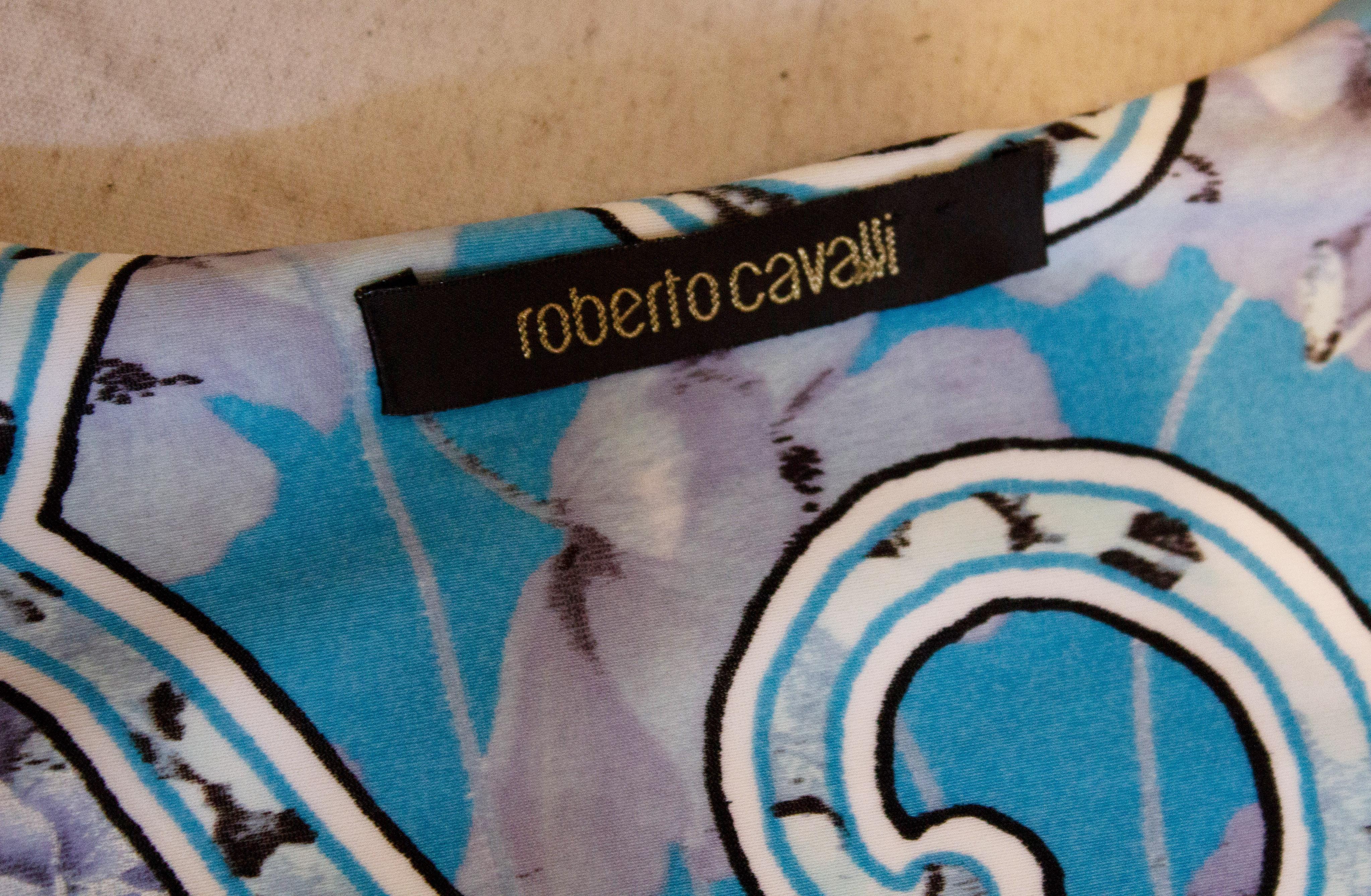 Ein hübsches Sommertop  von Roberto Cavalli. Das Oberteil hat einen V-Ausschnitt, Rüschen an den Ärmeln und einen blau-gelben Aufdruck mit Raffungen an der Brust.