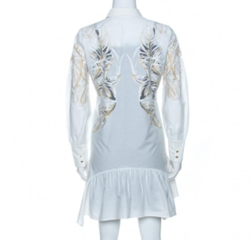 Cette robe chemise élégante et chic est signée Roberto Cavalli. Confectionné en coton mélangé, il se décline dans une superbe nuance de blanc. Il présente un imprimé de plumes brasso qui ajoute de l'intérêt et une touche de féminité. Il est doté