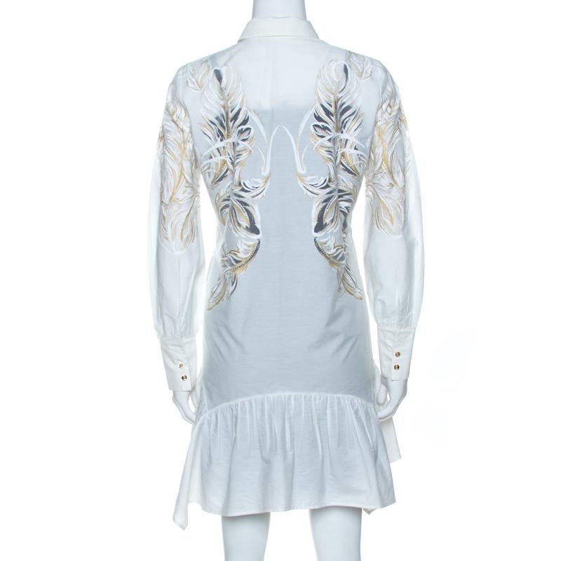 Dieses schicke und elegante Hemdkleid stammt aus dem Hause Roberto Cavalli. Es ist aus einer schönen Baumwollmischung gefertigt und in einem herrlichen Weißton gehalten. Der Federdruck aus Messing verleiht ihm einen interessanten und femininen