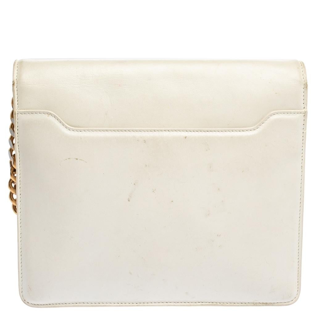 This lovely shoulder bag by Roberto Cavalli is stylish and striking. It has been crafted from white-hued leather and has a front flap that is adorned with embellishments. It has a spacious leather interior, gold-tone hardware, a chain-link strap