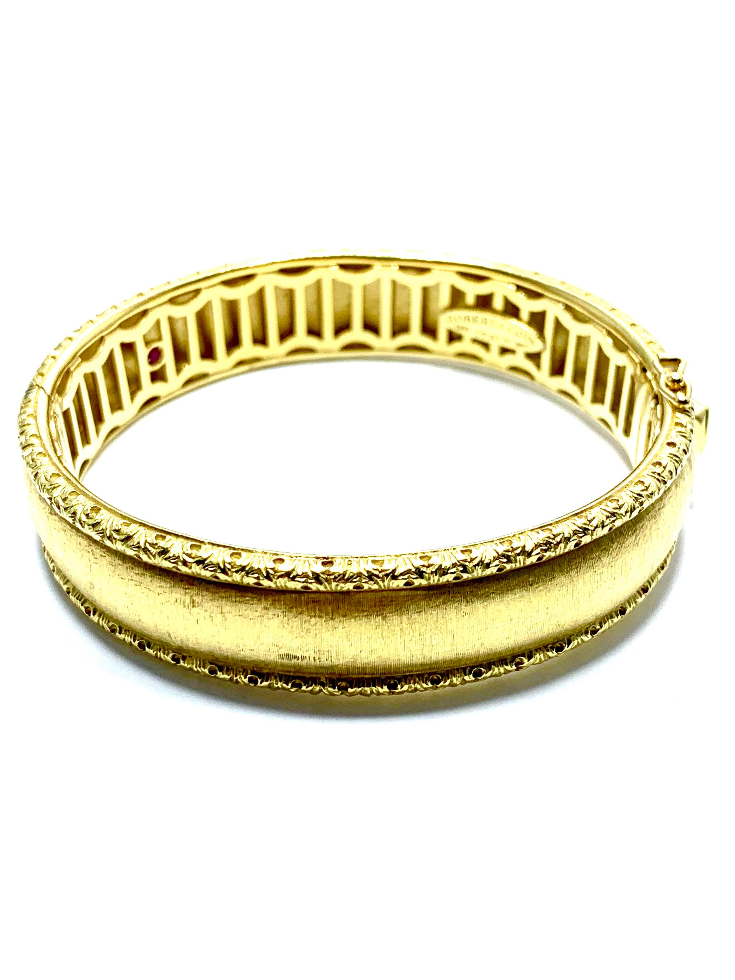 A beautiful 18 karat yellow gold bangle bracelet deigned by Roberto Coin.  The bracelet has a soft satin finish and features a marquise shaped ruby on the clasp, as well as a double safety catch.  The bracelet is slightly oval in shape to better fit